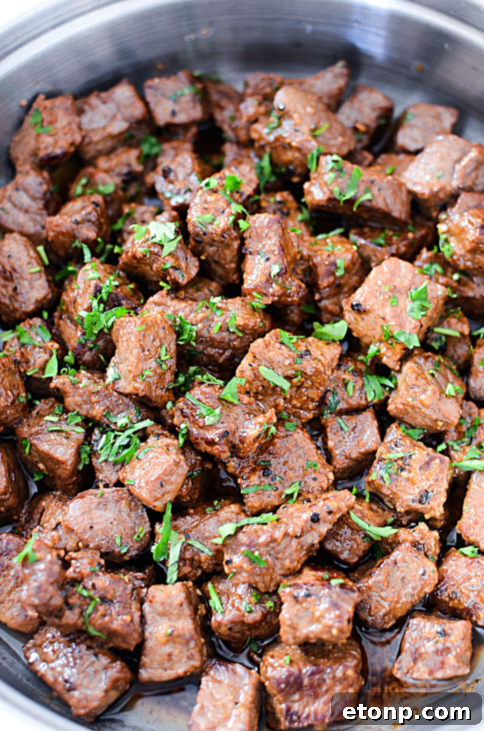 A serving of garlic butter steak bites with a fork, showing the tender interior and glossy sauce.