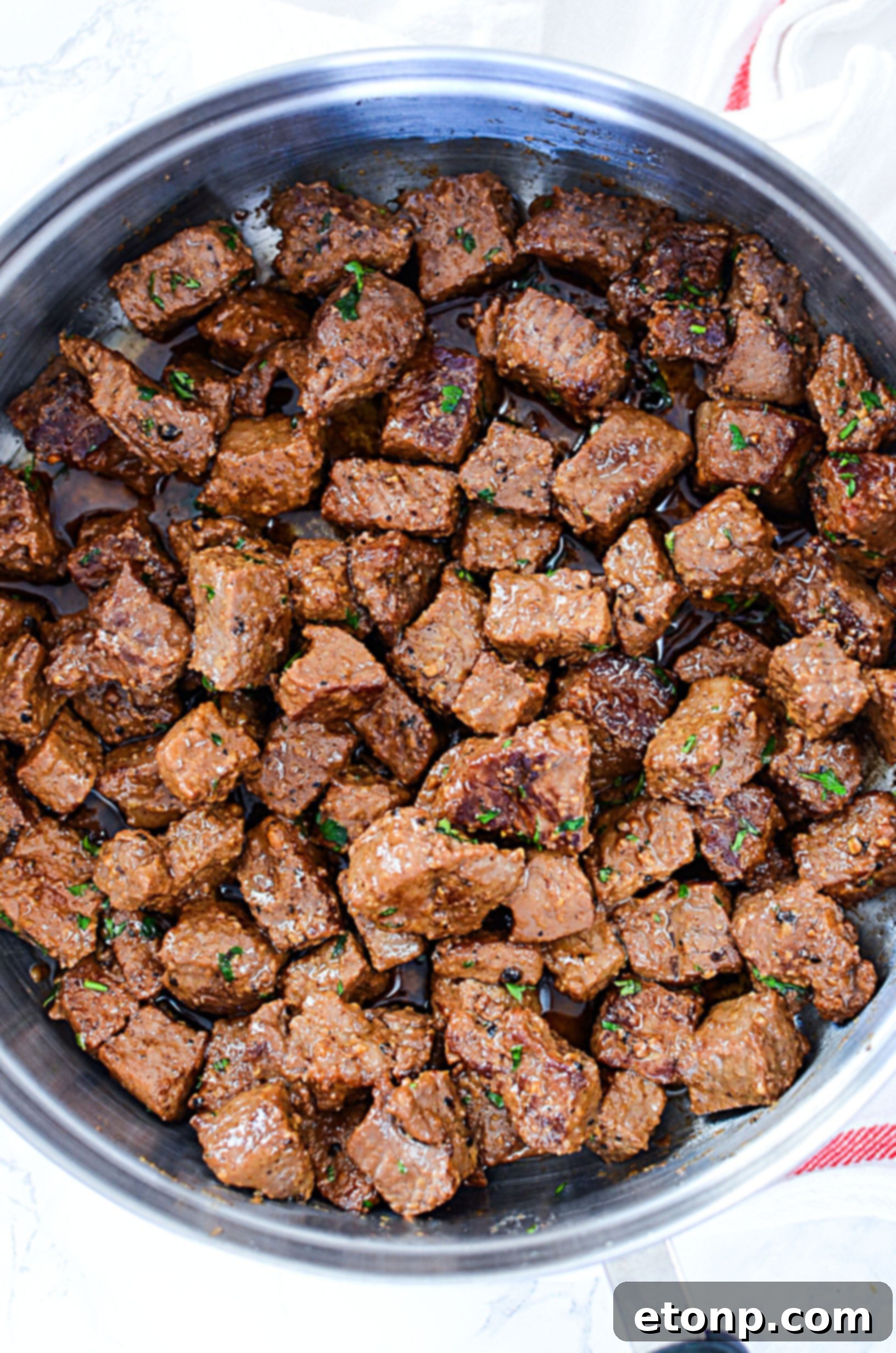 A close-up of a single steak bite on a toothpick, showing the beautiful sear and garlic bits.