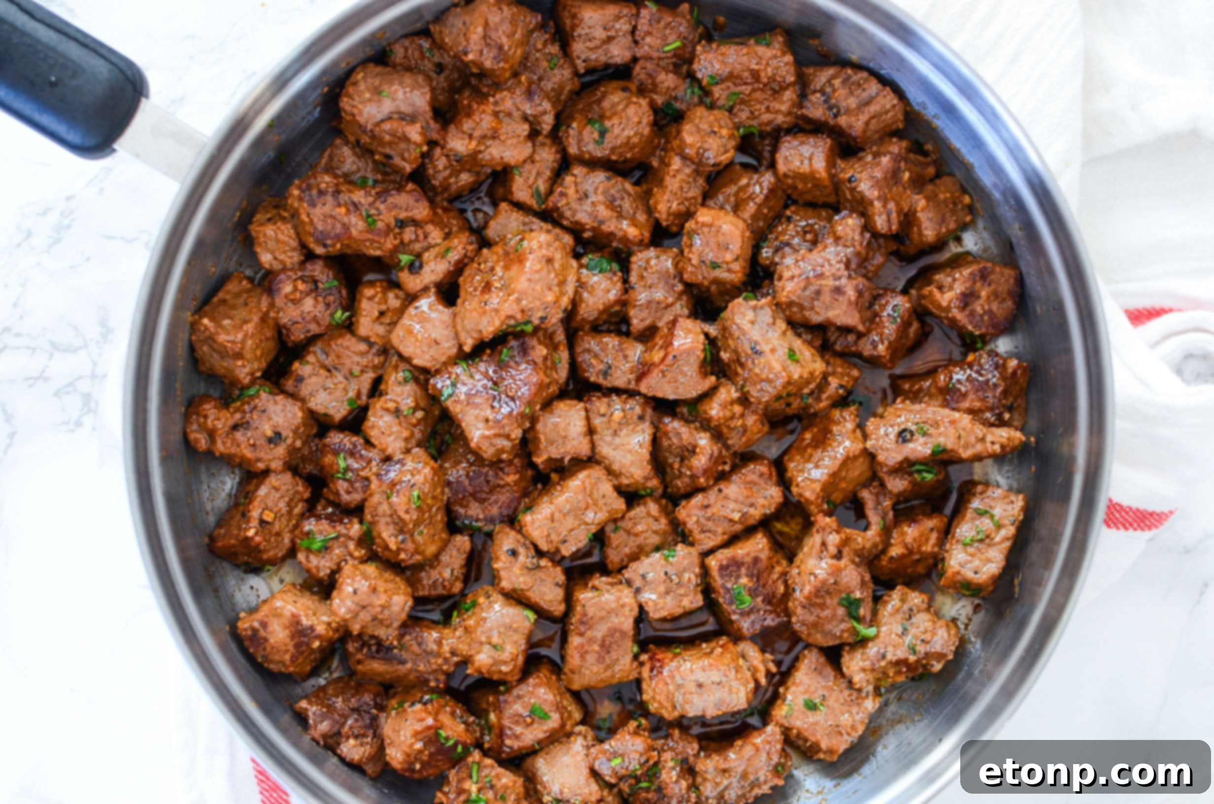A large platter of garlic butter steak bites, perfectly browned and coated in sauce.
