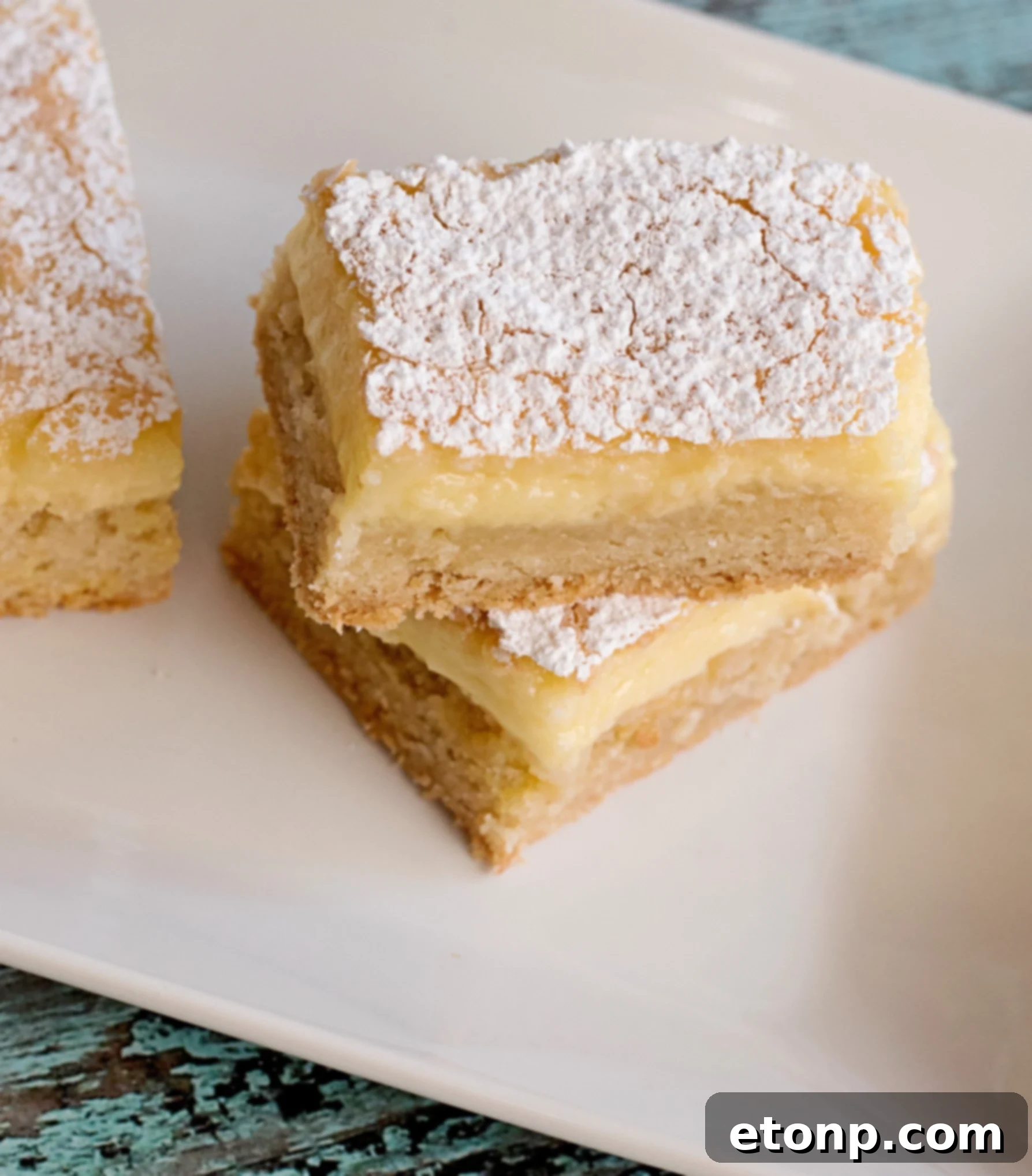 A close-up of a spoonful of vanilla bean ice cream melting over a warm Ooey Gooey Butter Bar.