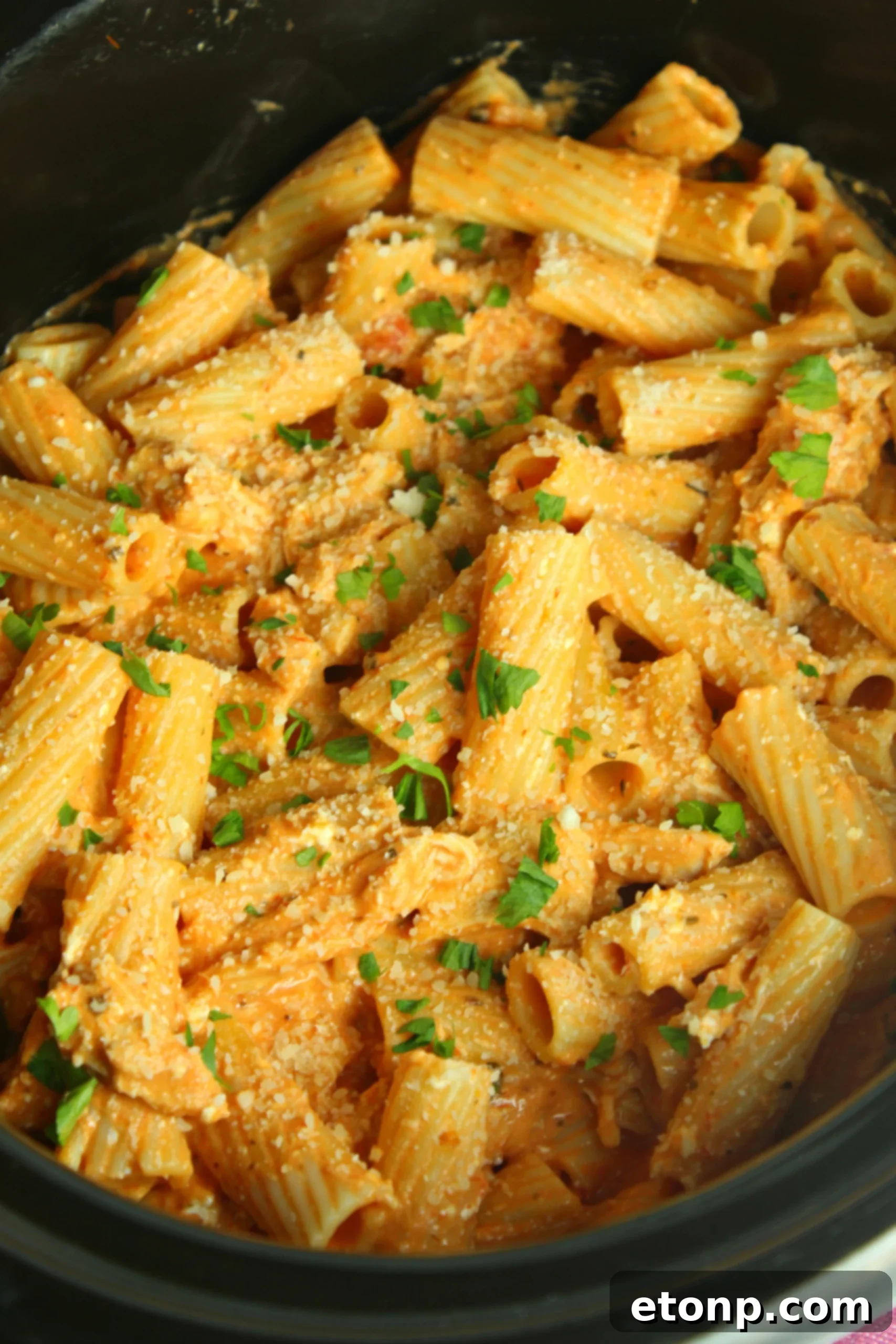A bowl of creamy chicken rigatoni pasta ready to be served, garnished with fresh herbs
