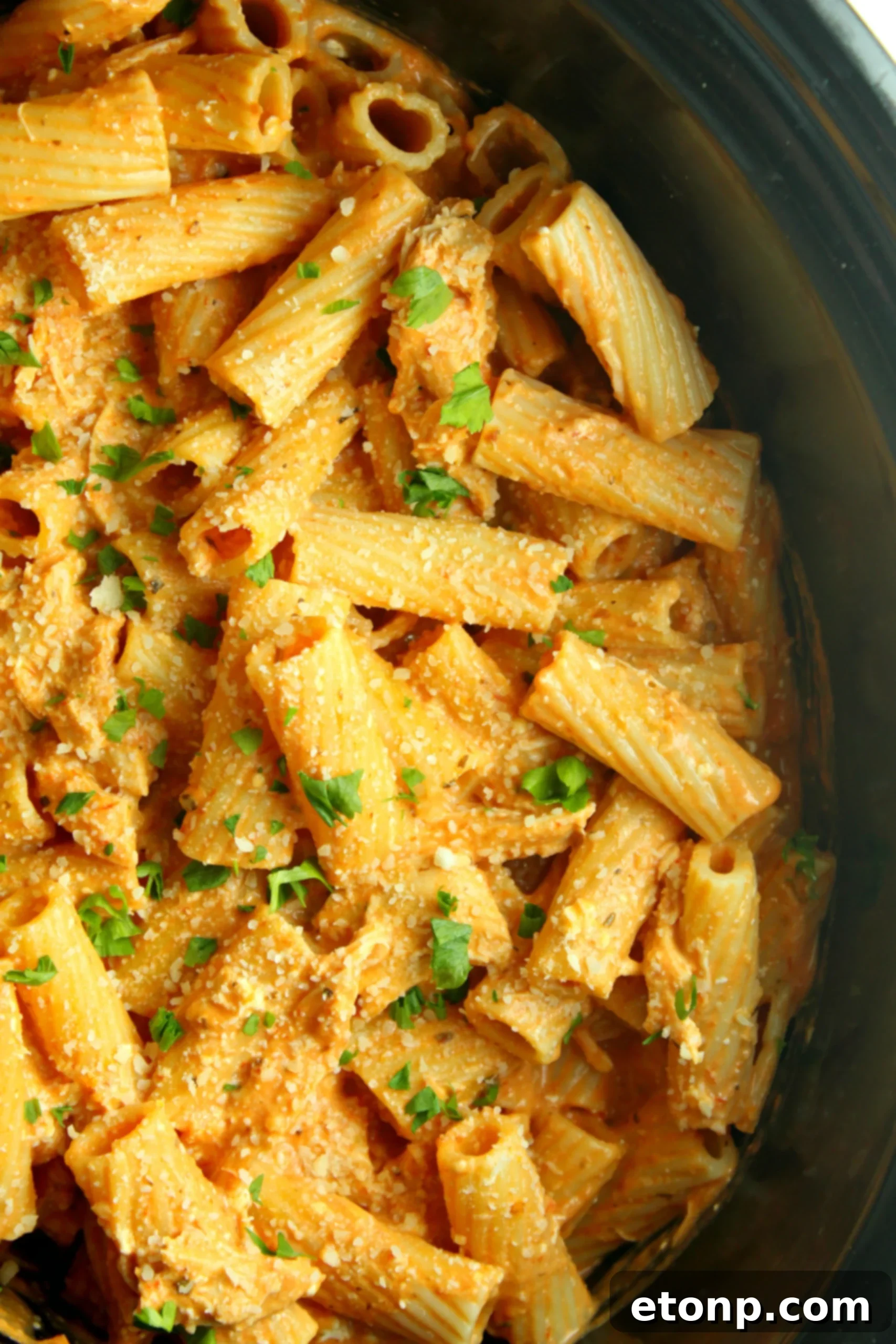 A serving of creamy chicken rigatoni in a bowl with a fork