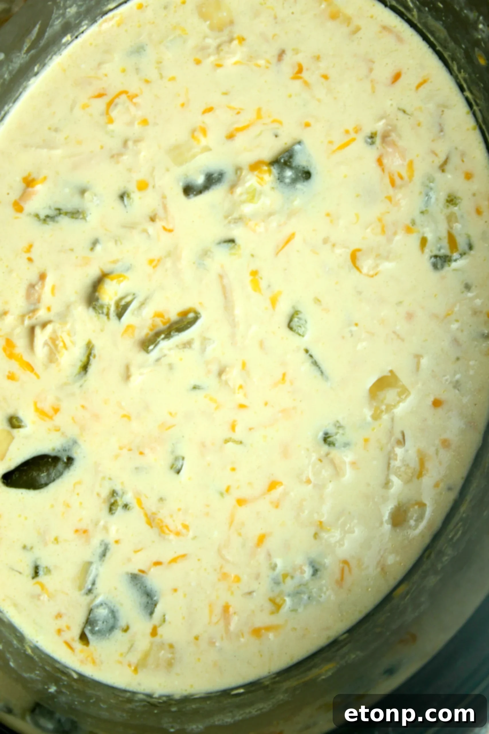 A close-up view of the rich, creamy texture of the Slow Cooker Chicken Chile Rellenos Soup, showing melted cheese and tender chicken