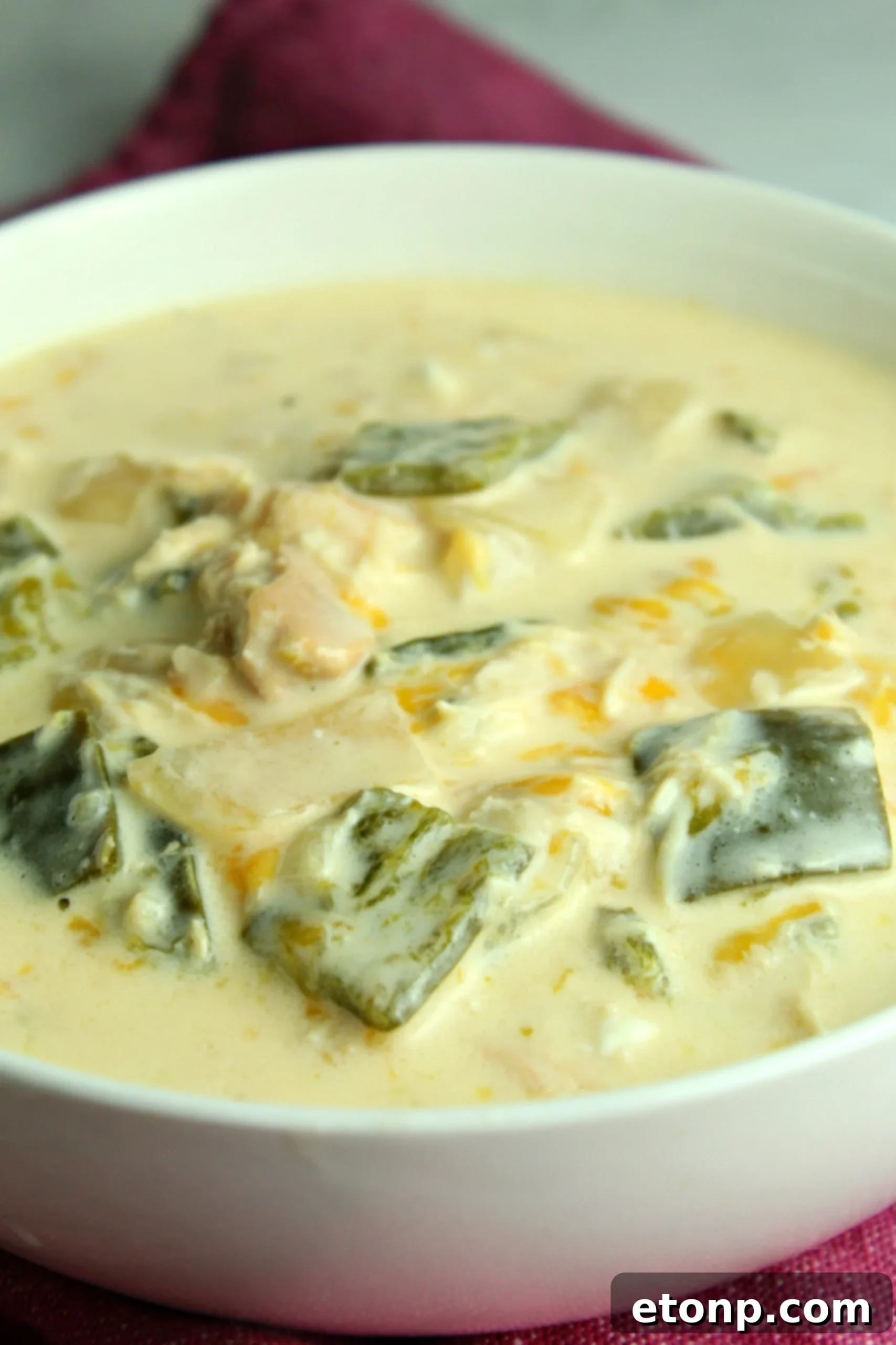 A beautifully presented single serving of Slow Cooker Chicken Chile Rellenos Soup in a white bowl, garnished with a lime wedge