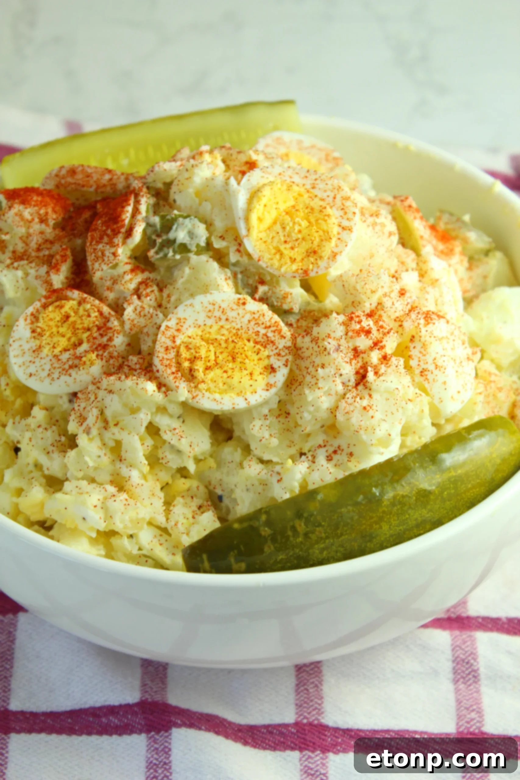 A large mixing bowl filled with the combined ingredients of dill pickle potato egg salad, ready for chilling.