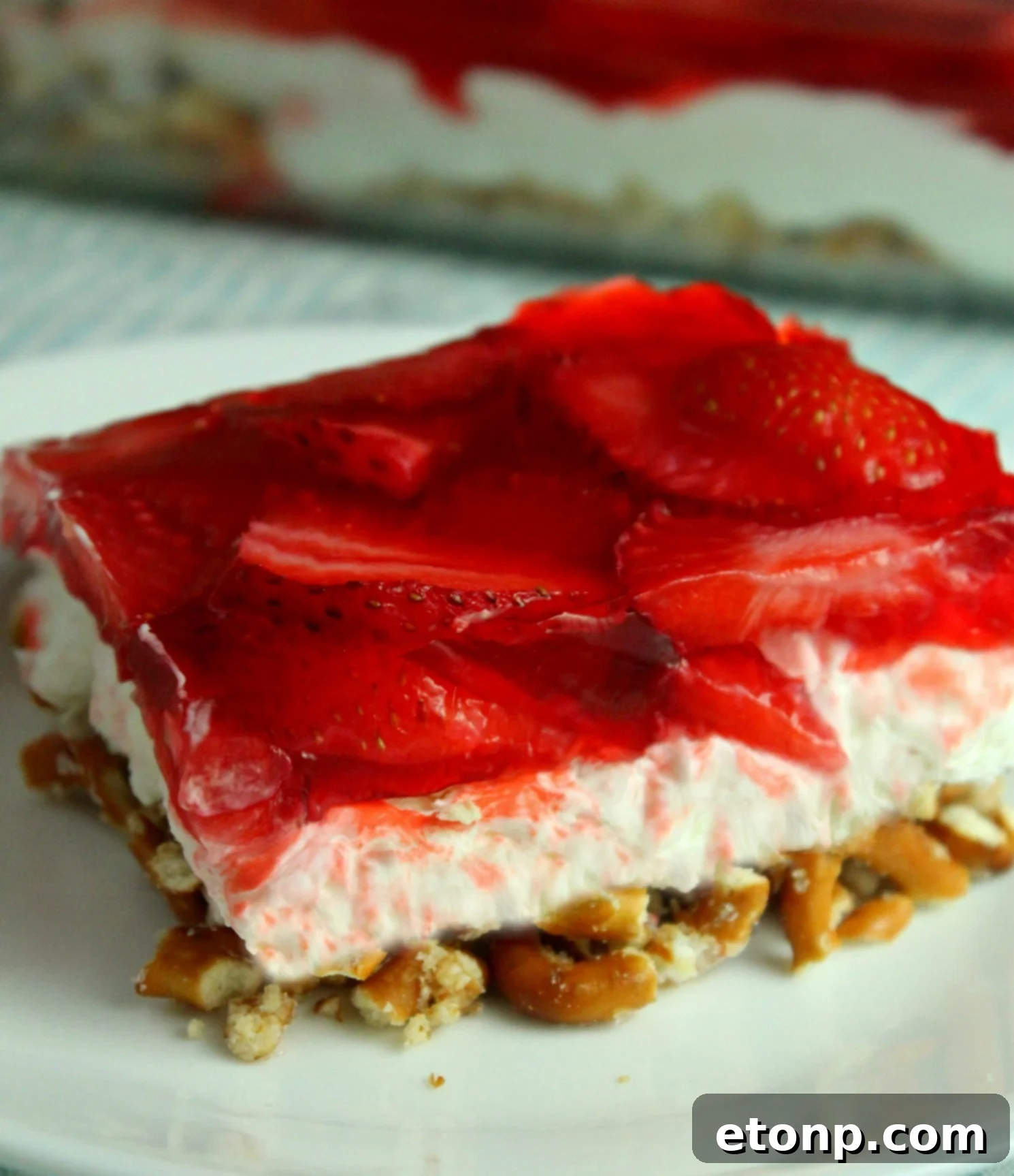 A beautifully presented slice of Strawberry Pretzel Salad, showing all three layers clearly on a serving plate.