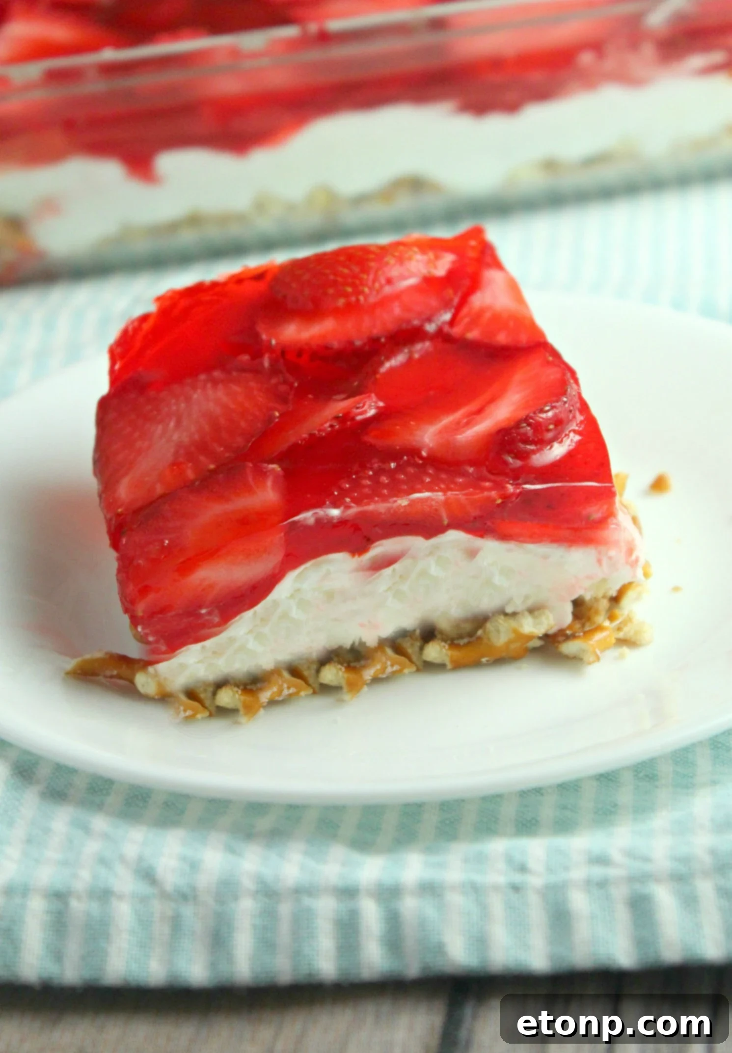 The finished Strawberry Pretzel Salad, glistening with Jell-O and fresh strawberries, ready for serving.