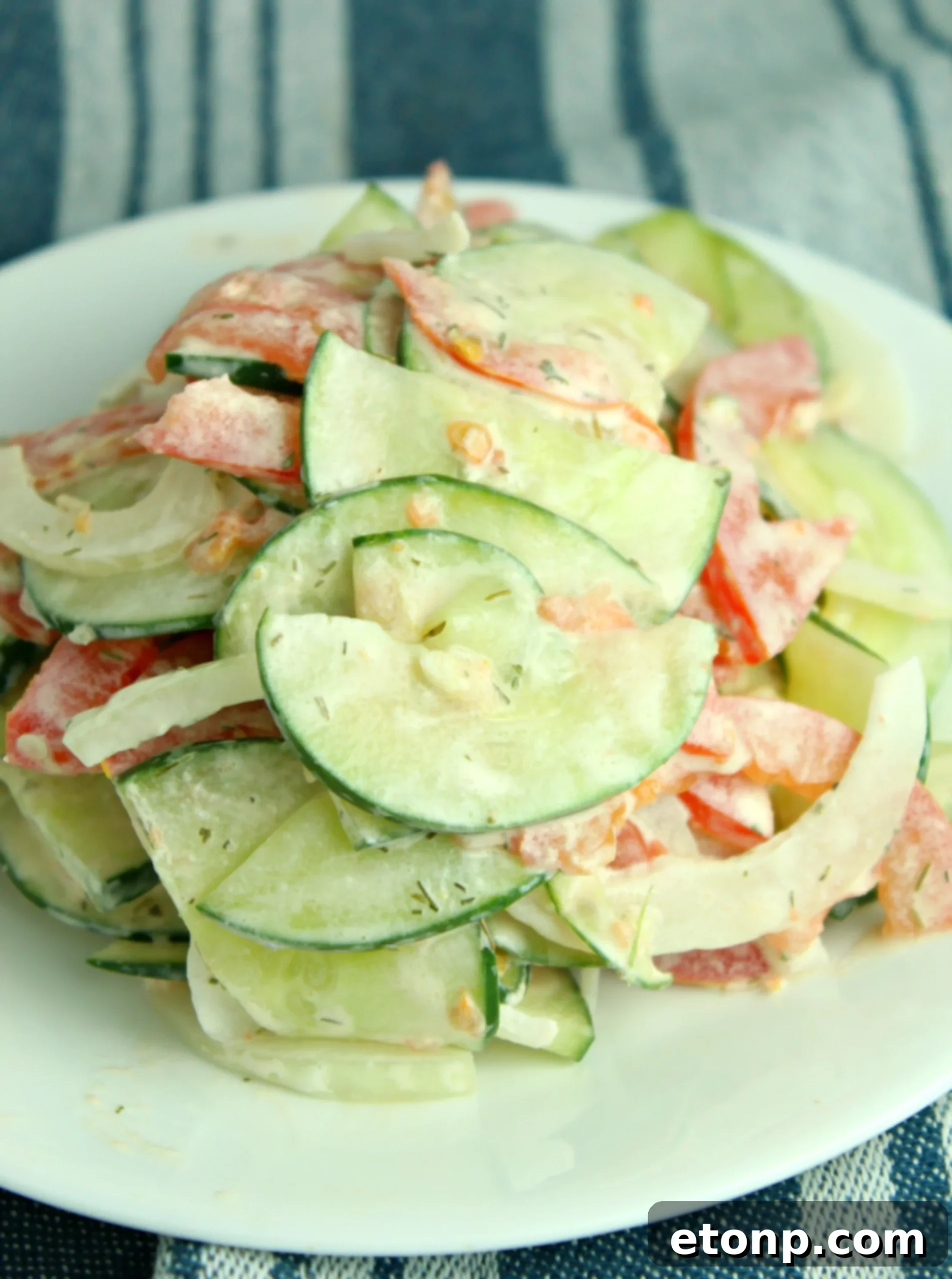 Overhead shot of creamy cucumber tomato salad in a modern kitchen setting, emphasizing its fresh ingredients.