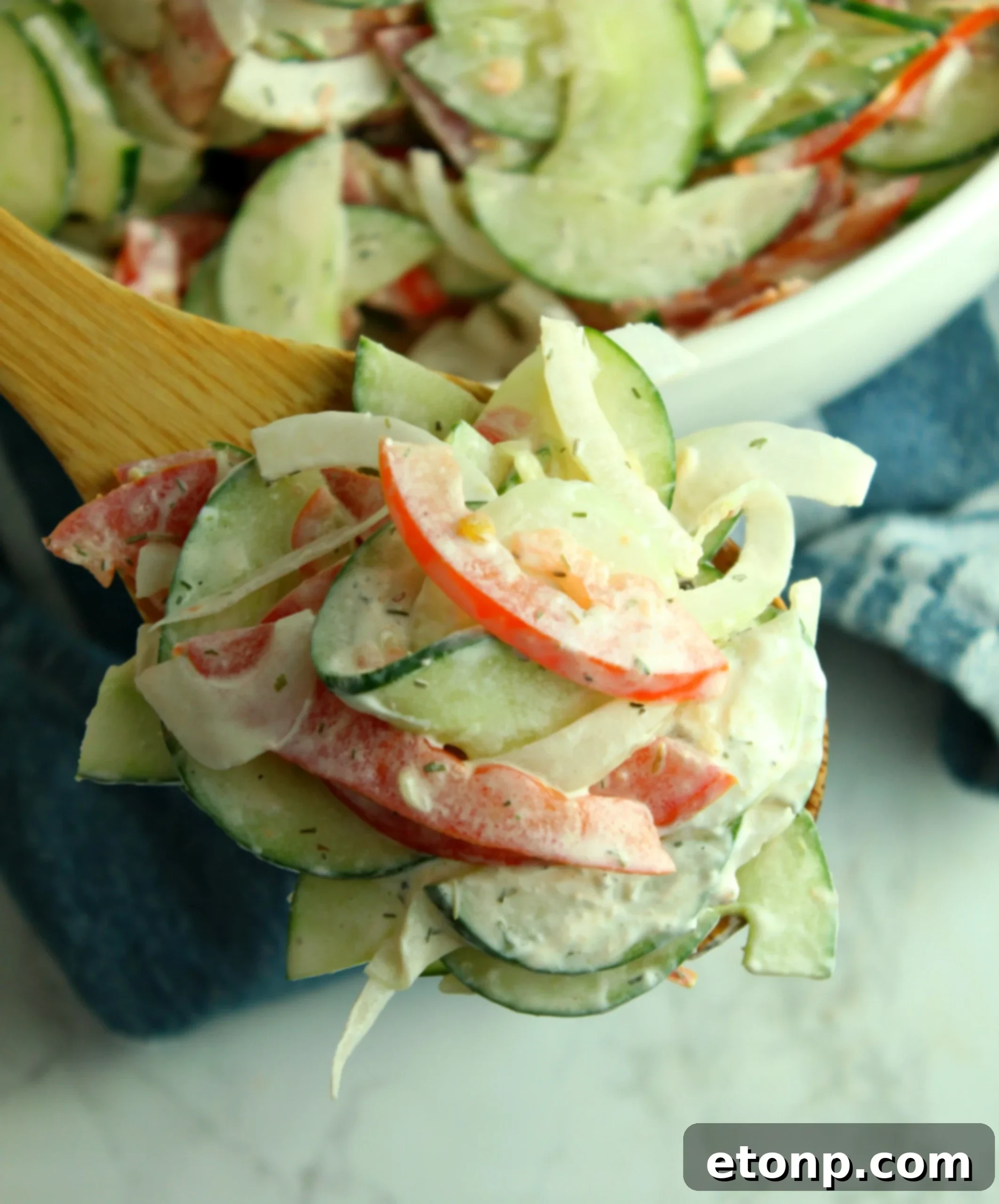 A serving of creamy cucumber tomato salad in a white bowl, garnished with fresh dill, ready for enjoyment.