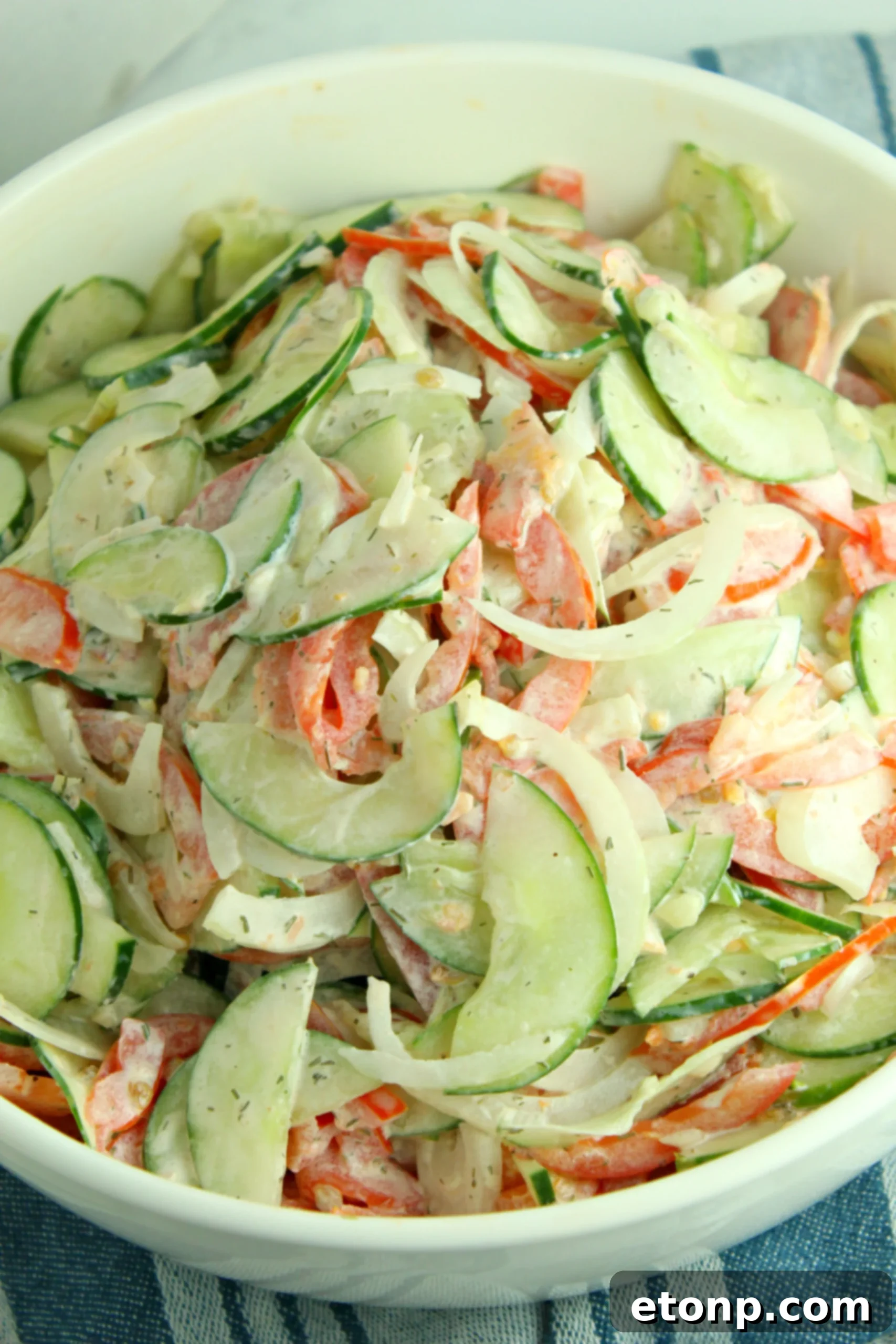 Side view of creamy cucumber tomato salad, showing the layers of fresh vegetables and creamy dressing.