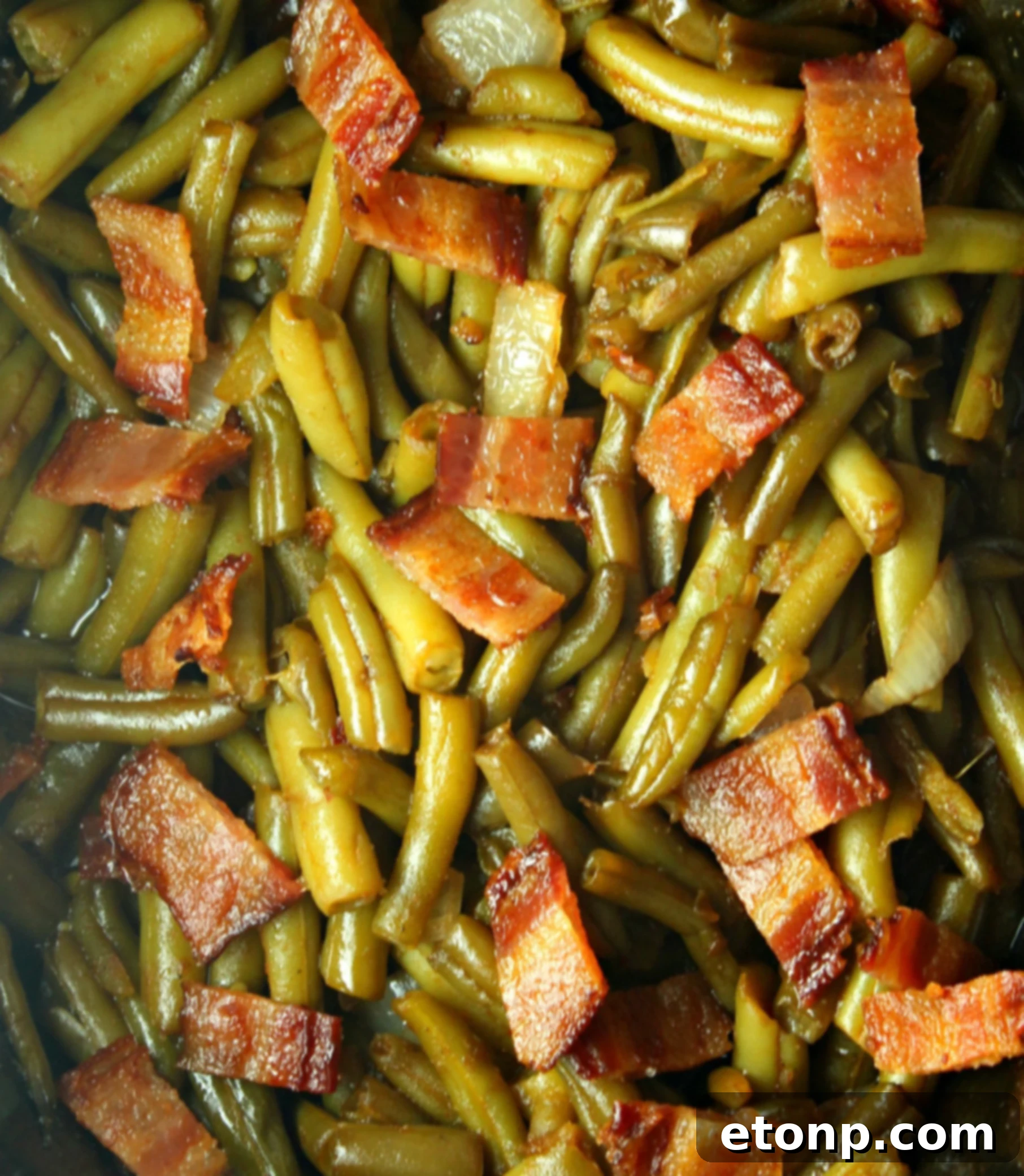 Close-up of Slow Cooker Buttery Bacon Green Beans in a serving dish, showing crispy bacon pieces