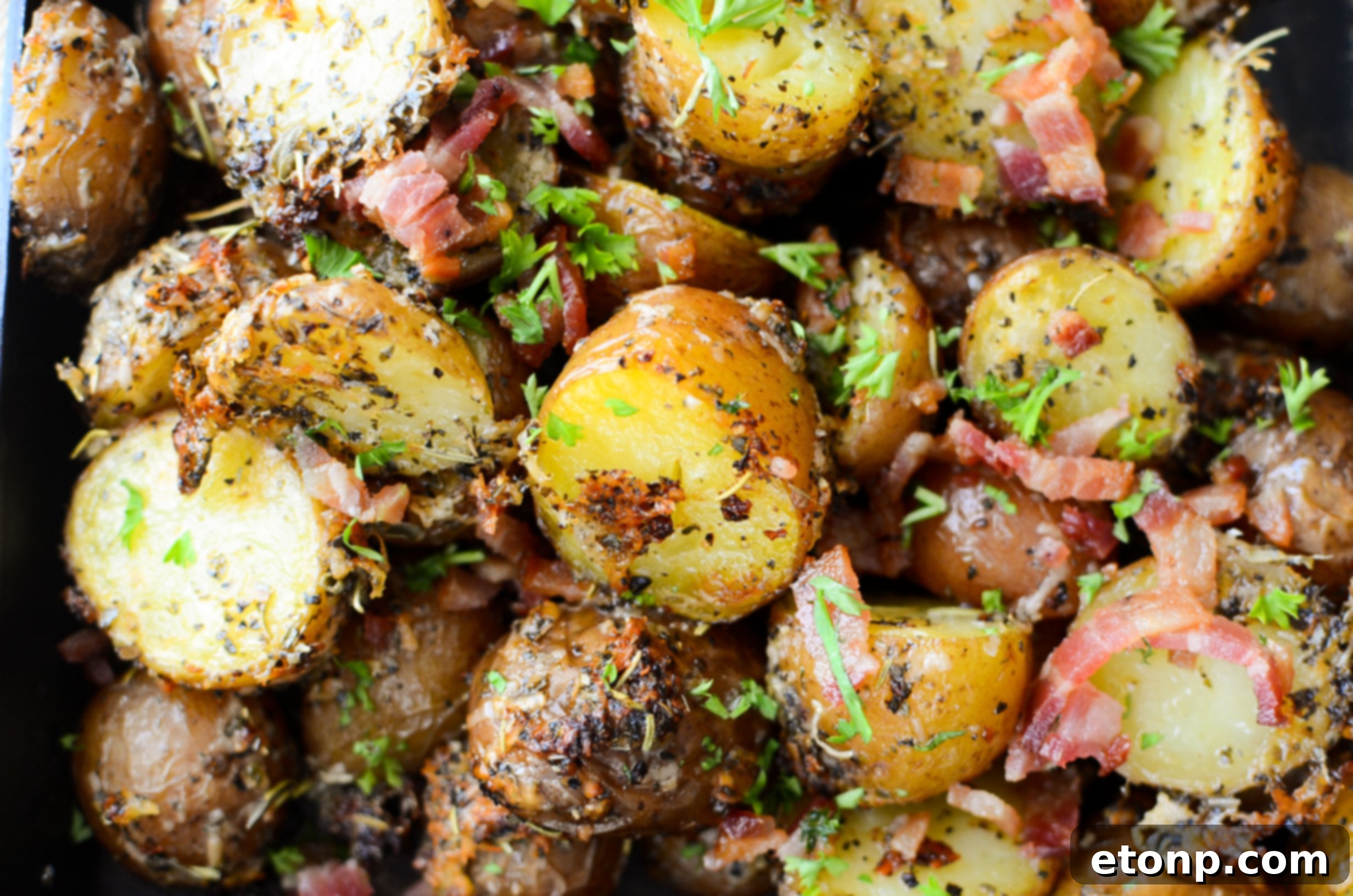 Close-up of Parmesan Crusted Roasted Potatoes in a baking dish, highlighting the golden brown crust and bacon pieces.