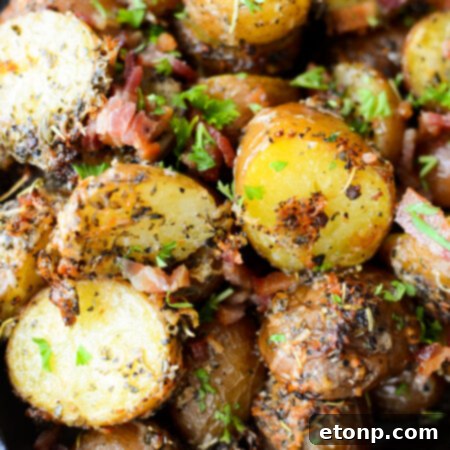 A close-up of a serving of Parmesan Crusted Roasted Potatoes with fresh herbs, emphasizing the crispy texture.