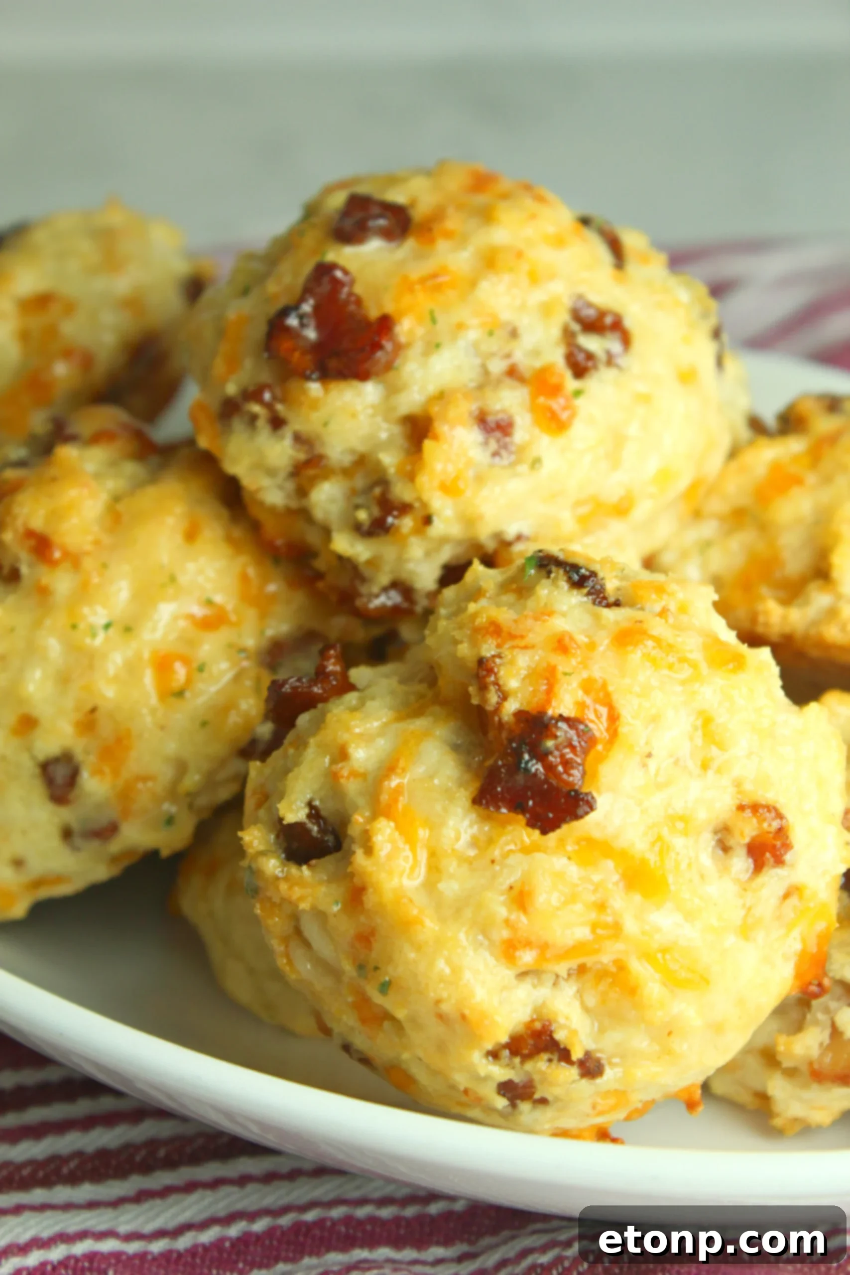 Close-up of a stack of warm Cheesy Bacon Garlic Biscuits, highlighting their texture and the generous amount of cheese and bacon.