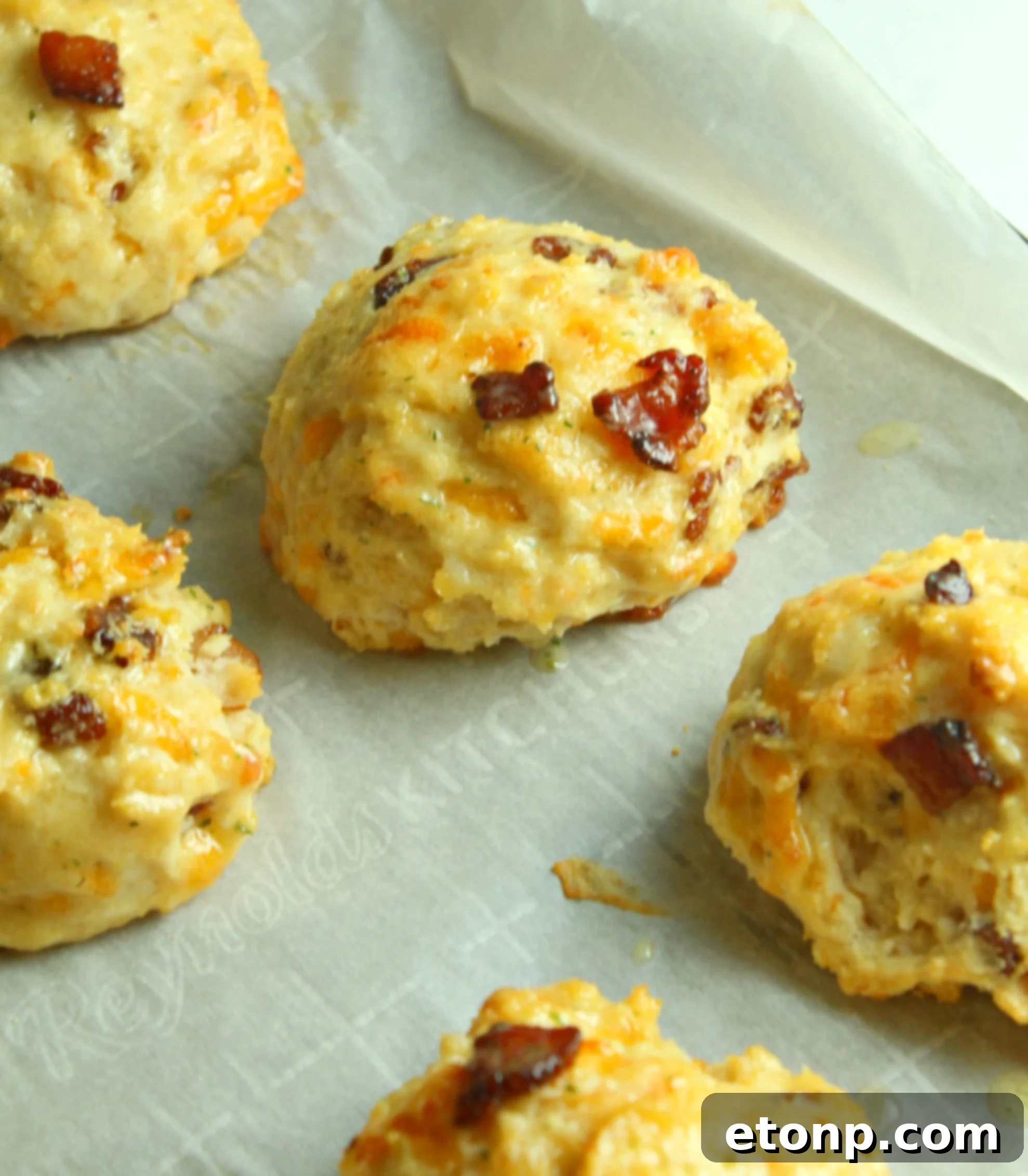 A single Cheesy Bacon Garlic Biscuit, pulled apart to reveal its soft, airy interior filled with cheese and bacon bits.