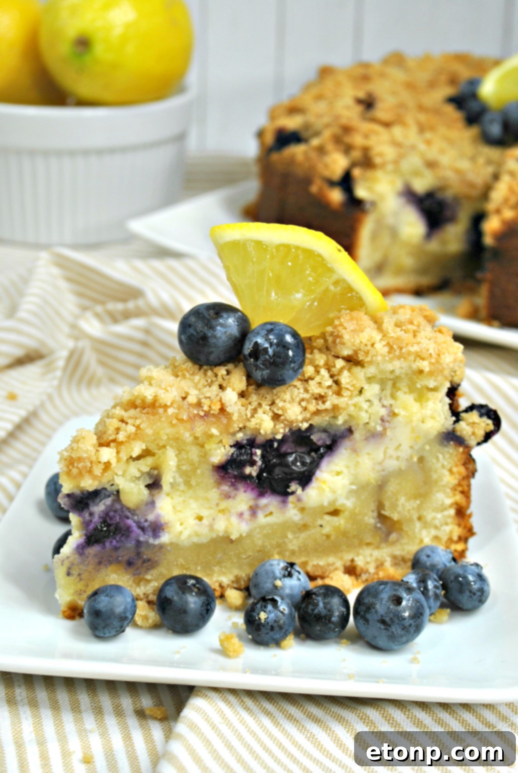 A glorious slice of Blueberry Cream Cheese Coffee Cake with a visible swirl of cream cheese, streusel topping, and juicy blueberries.