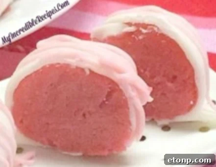 Close-up of a strawberry cheesecake truffle cut in half, showing the soft center