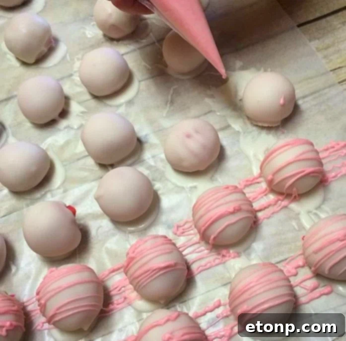 A hand dipping a truffle into melted white chocolate