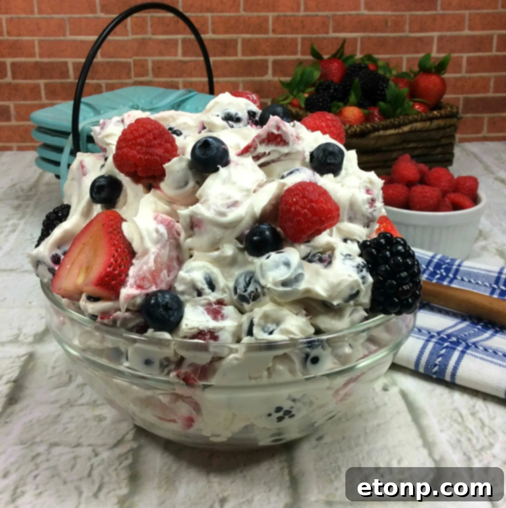 A close-up view of the creamy cheesecake topping generously coating the assorted berries in a Cheesecake Summer Berry Salad, highlighting its smooth texture.