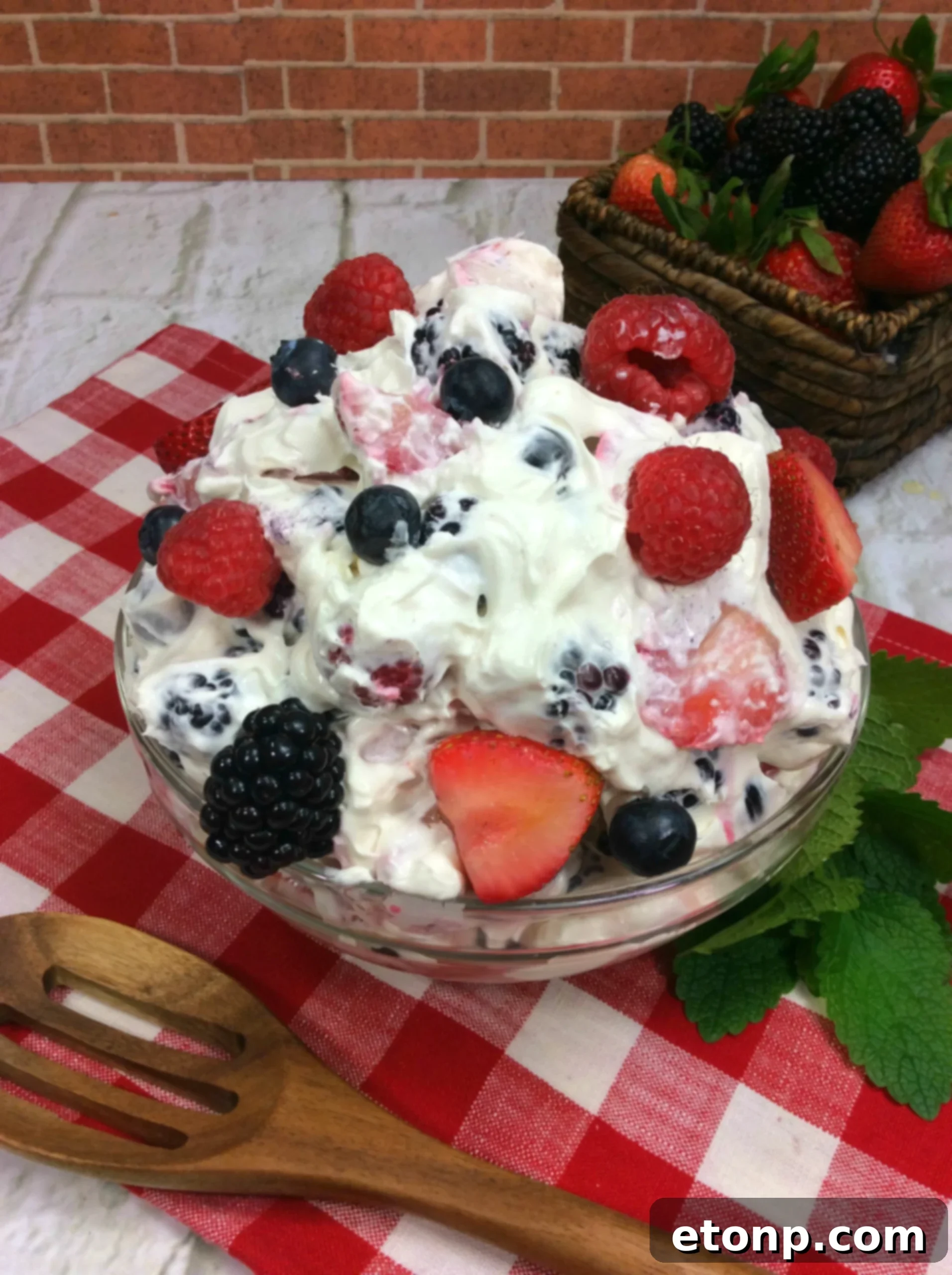 An arrangement of fresh, vibrant berries and a bowl of the creamy cheesecake topping, ready to be combined for the salad.