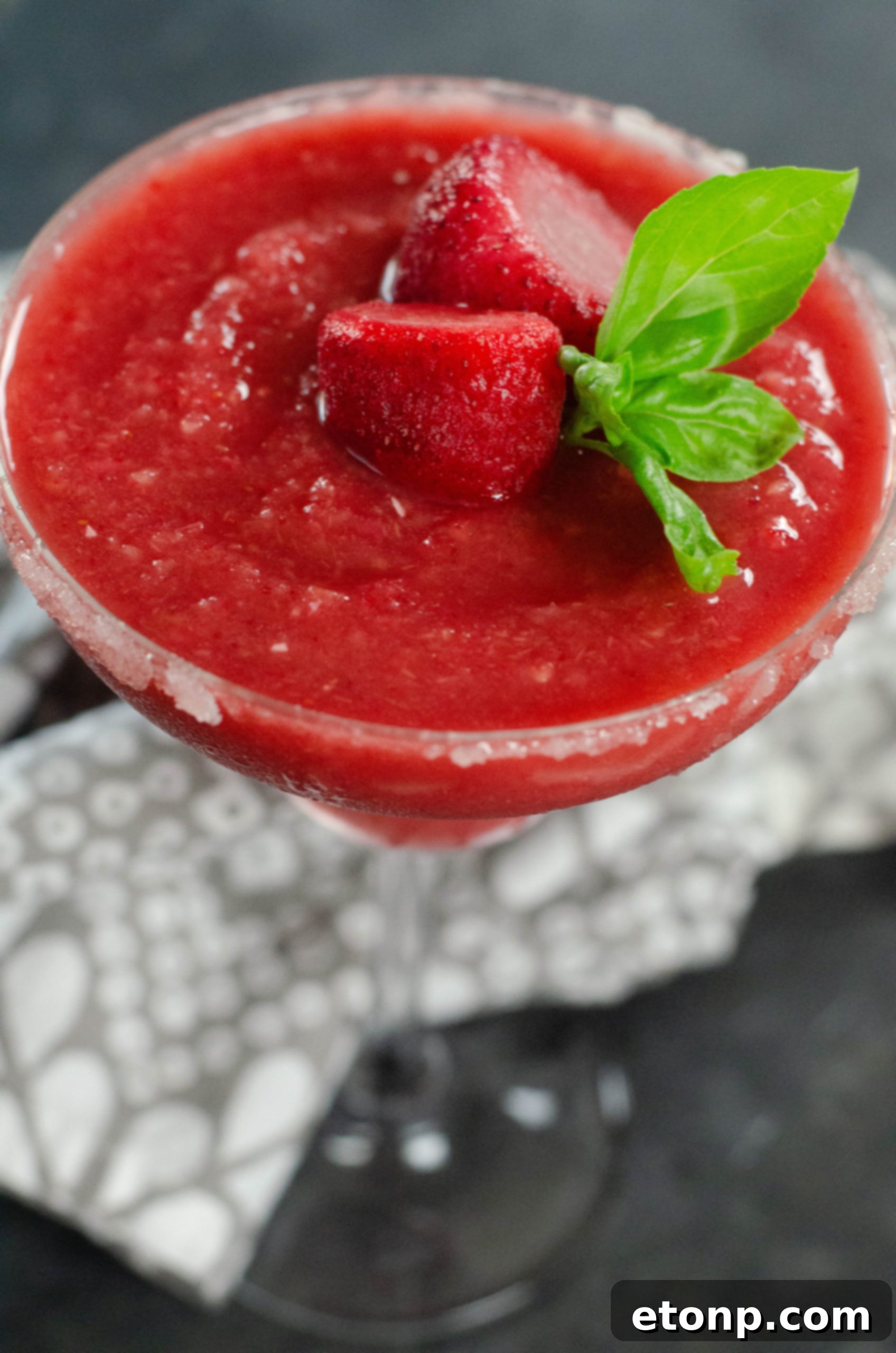 A beautifully garnished strawberry daiquiri in a stemmed glass, ready to be enjoyed.