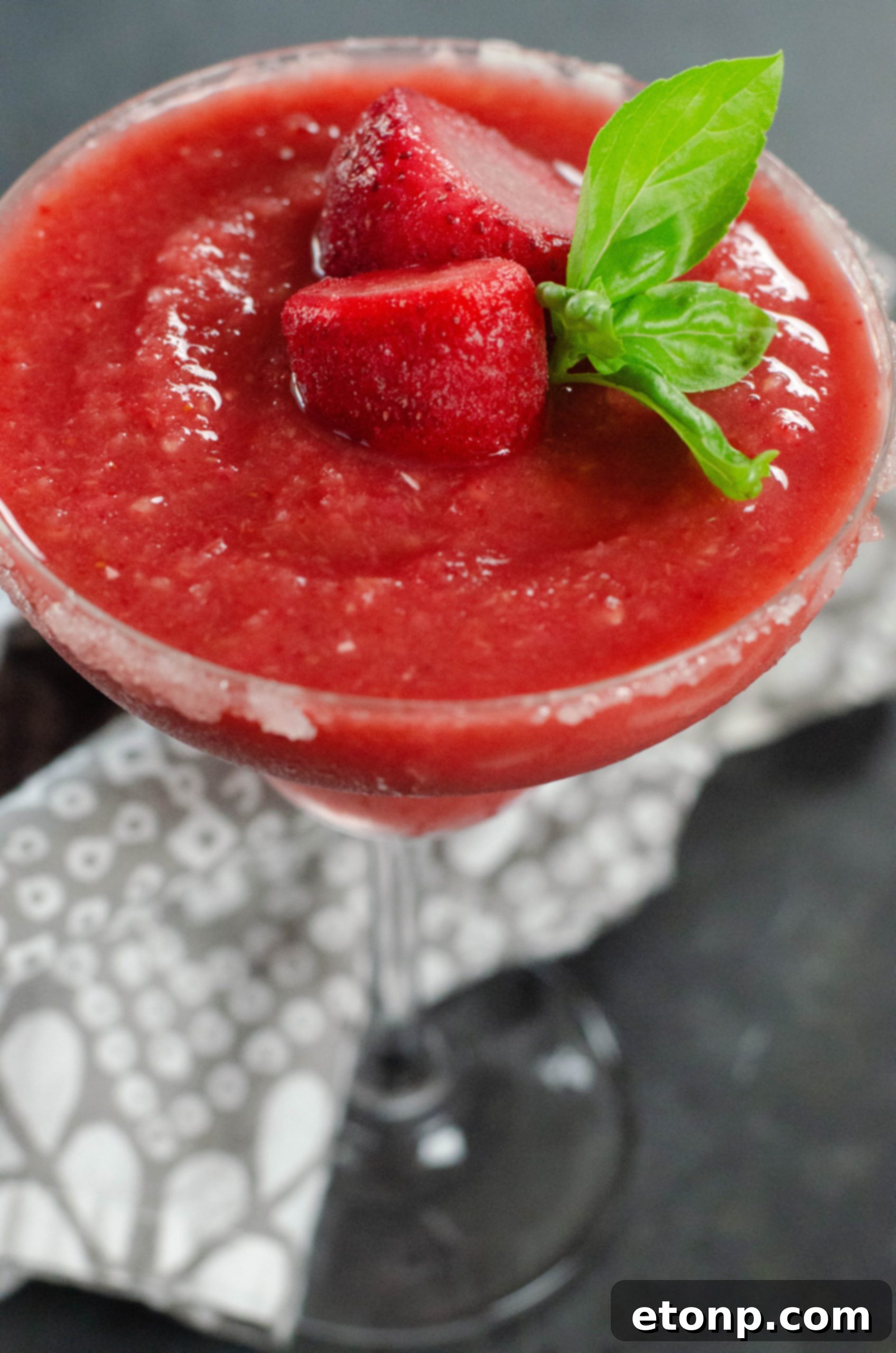 The blended strawberry daiquiri mixture being poured into a glass, showcasing its vibrant color and smooth texture.