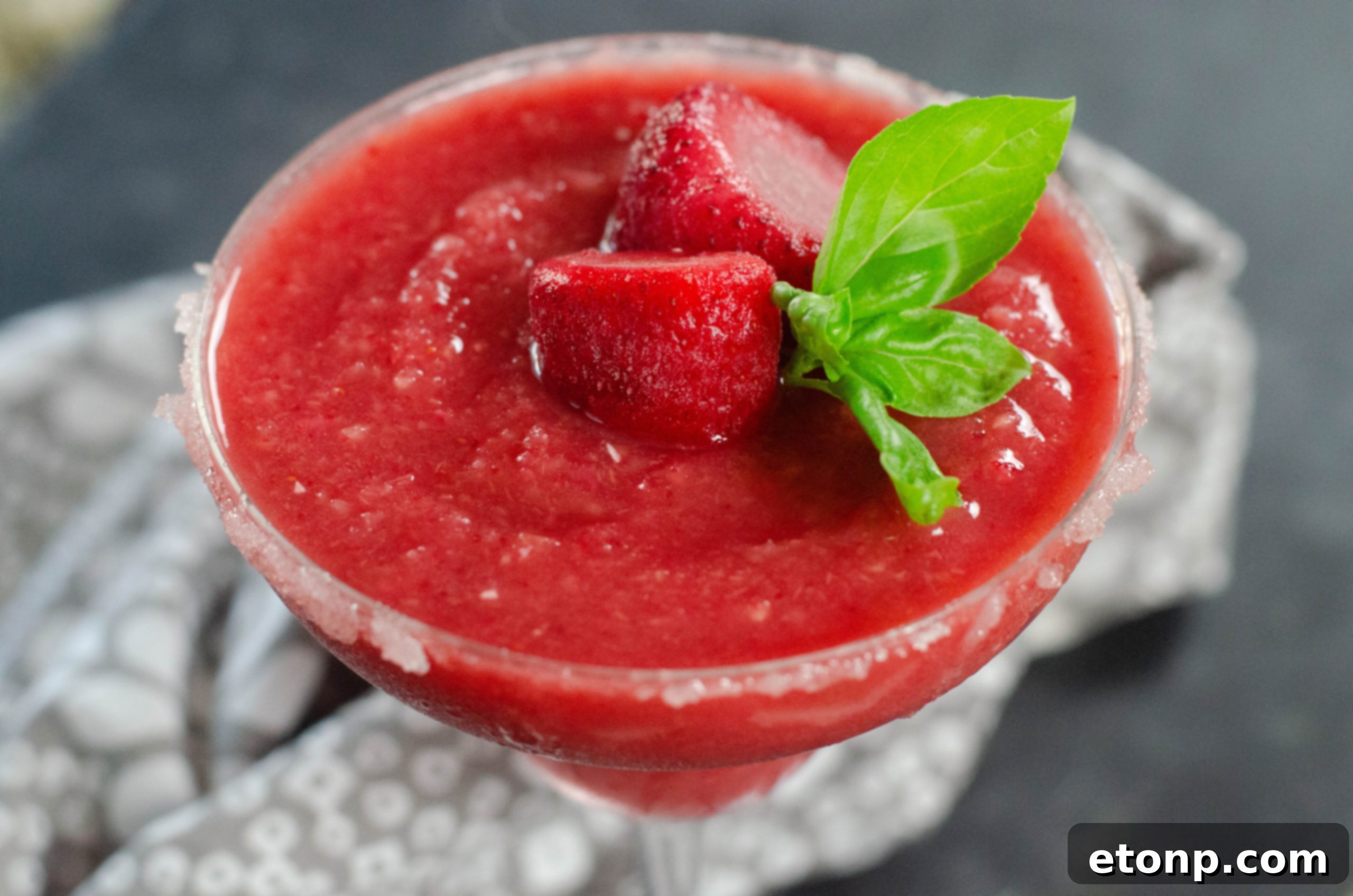 A close-up of the perfectly blended Strawberry Daiquiri, emphasizing its smooth texture and rich color.