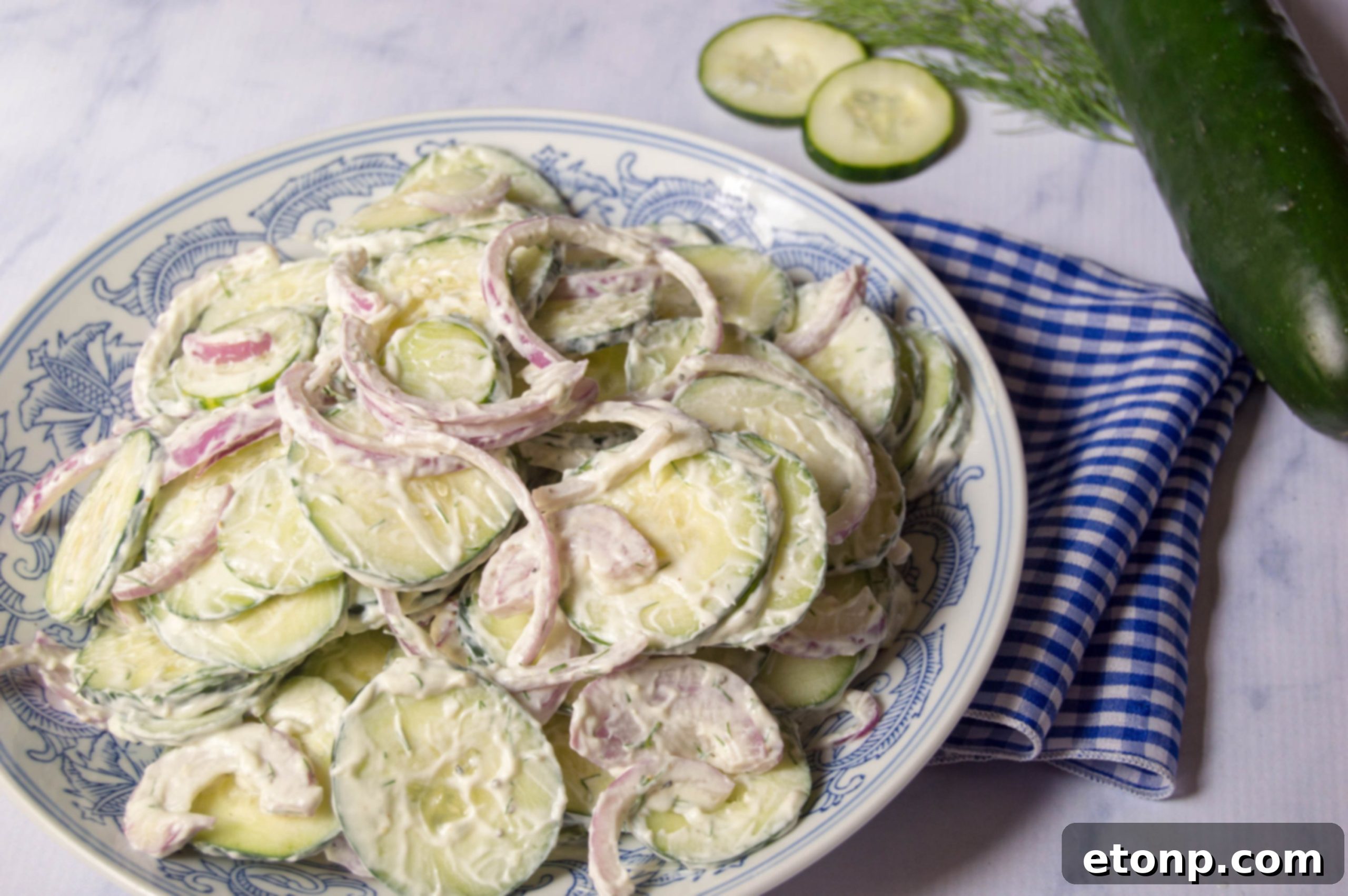 A large serving bowl full of creamy cucumber salad