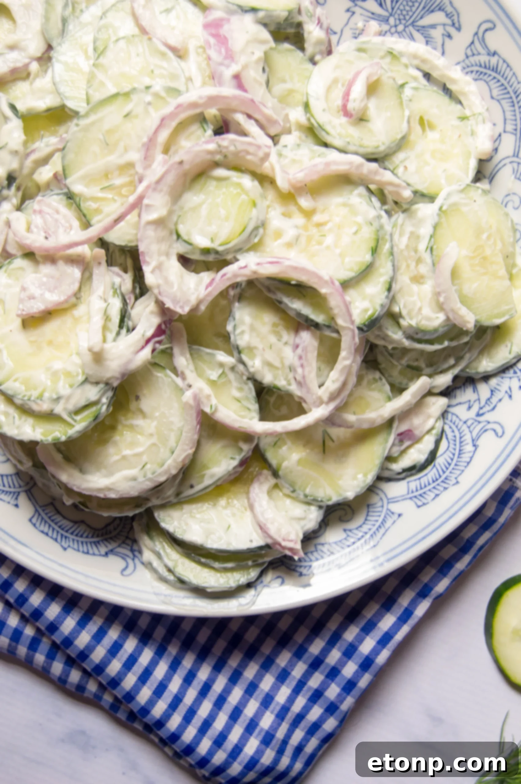 A bowl of creamy cucumber salad with a fresh sprig of dill
