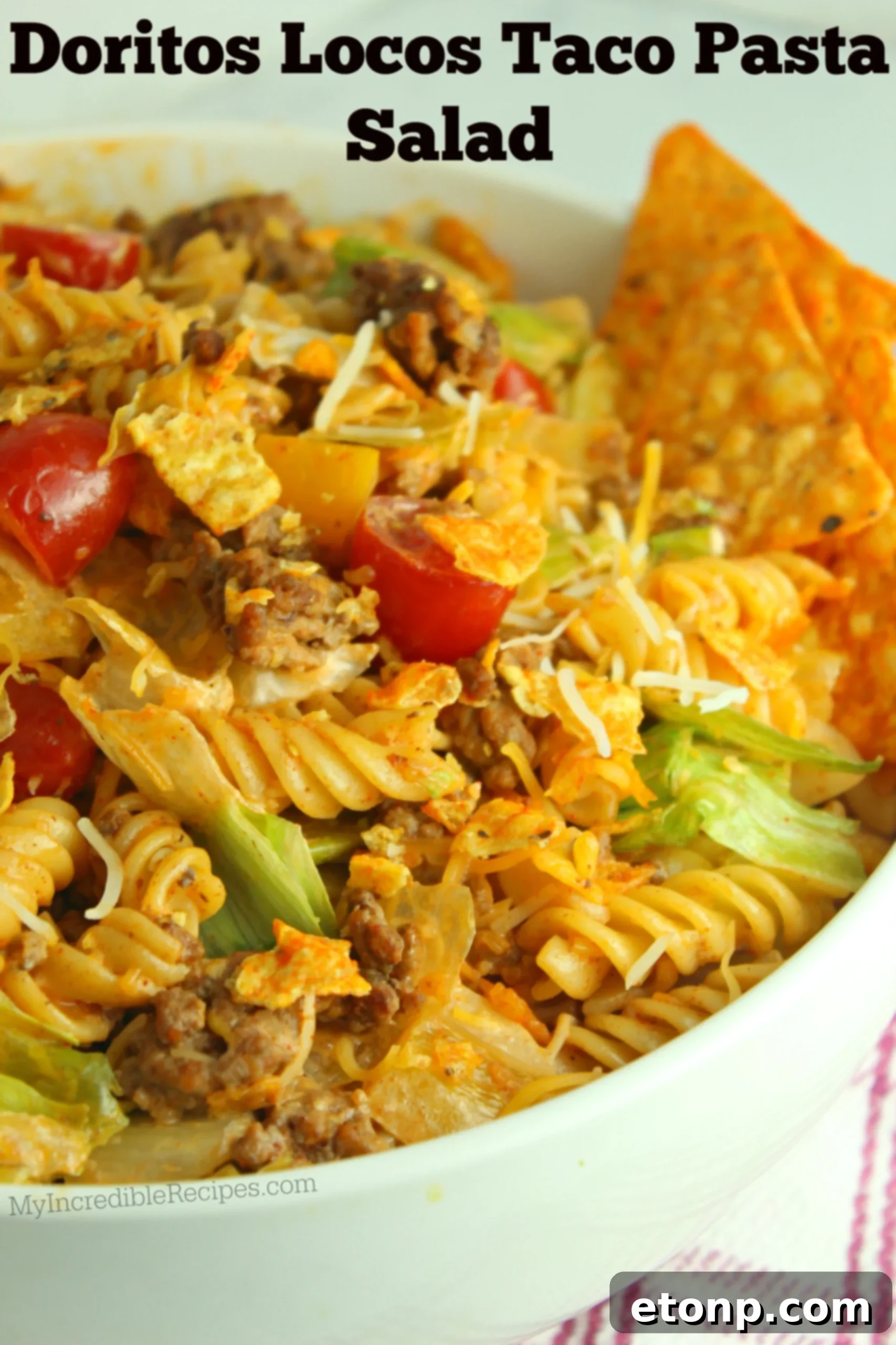 A vibrant bowl of Doritos Locos Taco Pasta Salad, rich with ground beef, pasta, cheese, and vegetables, topped with crushed Doritos and a dollop of sour cream.
