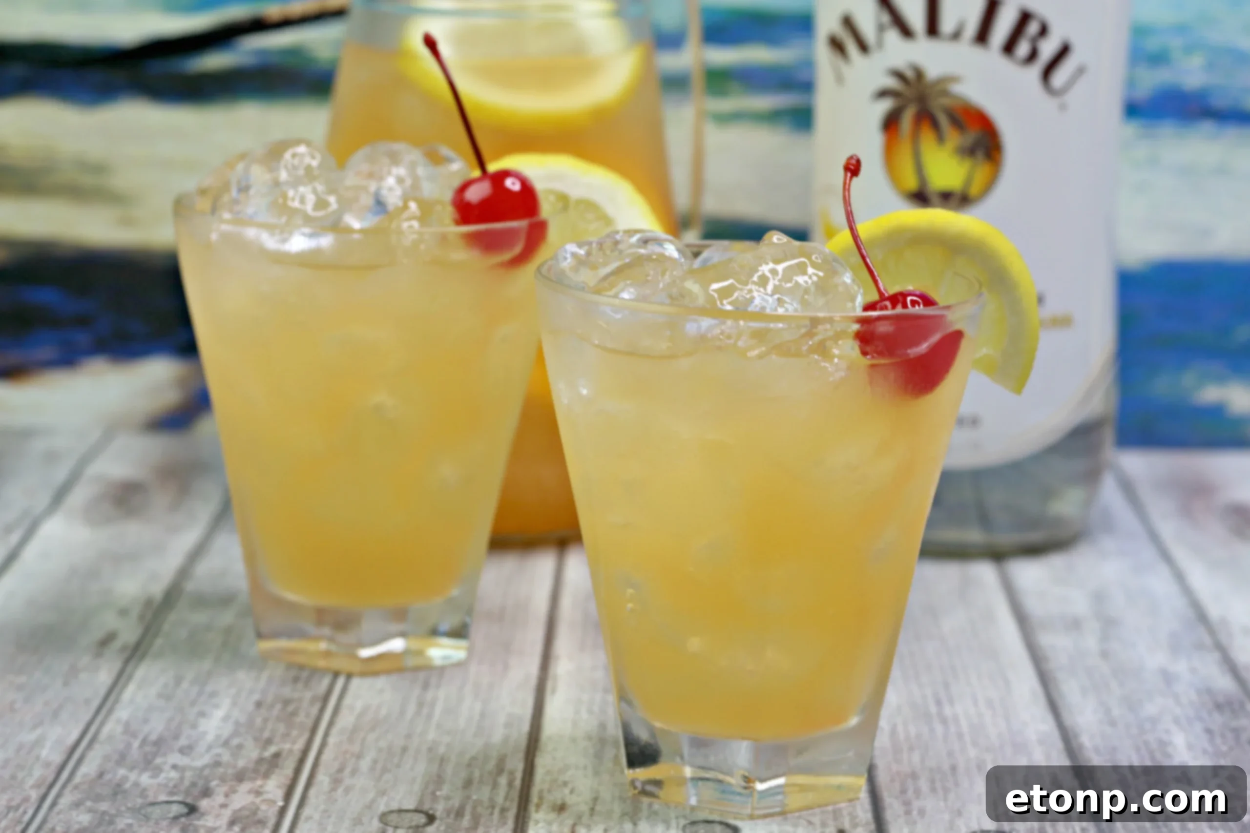 A close-up of a slushy Banana Rum Punch in a glass, with ice crystals visible and a garnish of an orange slice.