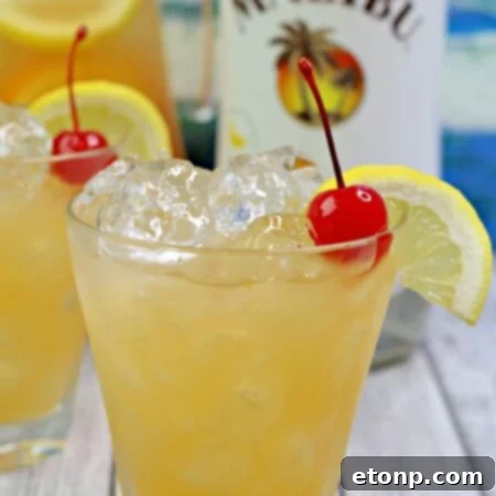 A vibrant glass of Banana Rum Punch, garnished with fresh orange and cherry, set against a festive background.