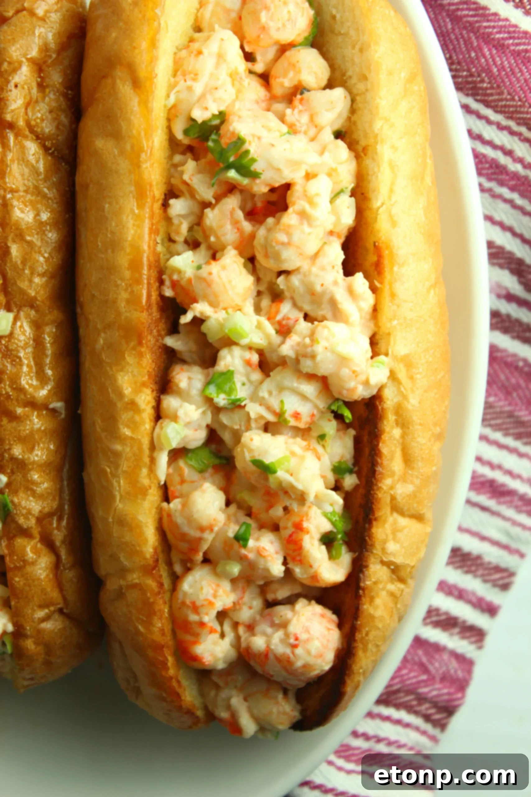 Hand holding a freshly made lobster roll, showcasing the generous filling
