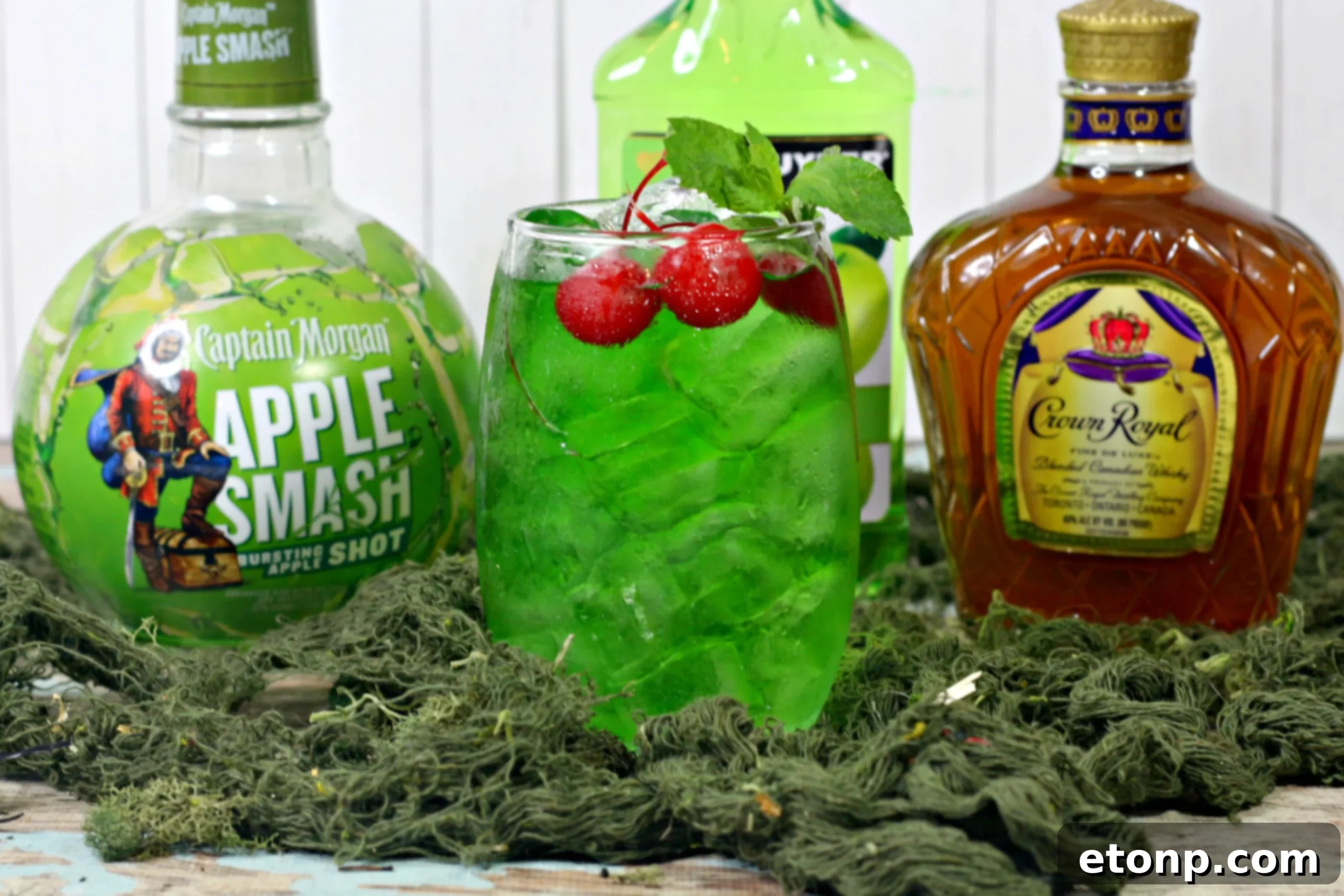 Two vibrant green Liquid Marijuana Cocktails with apple garnishes on a rustic table