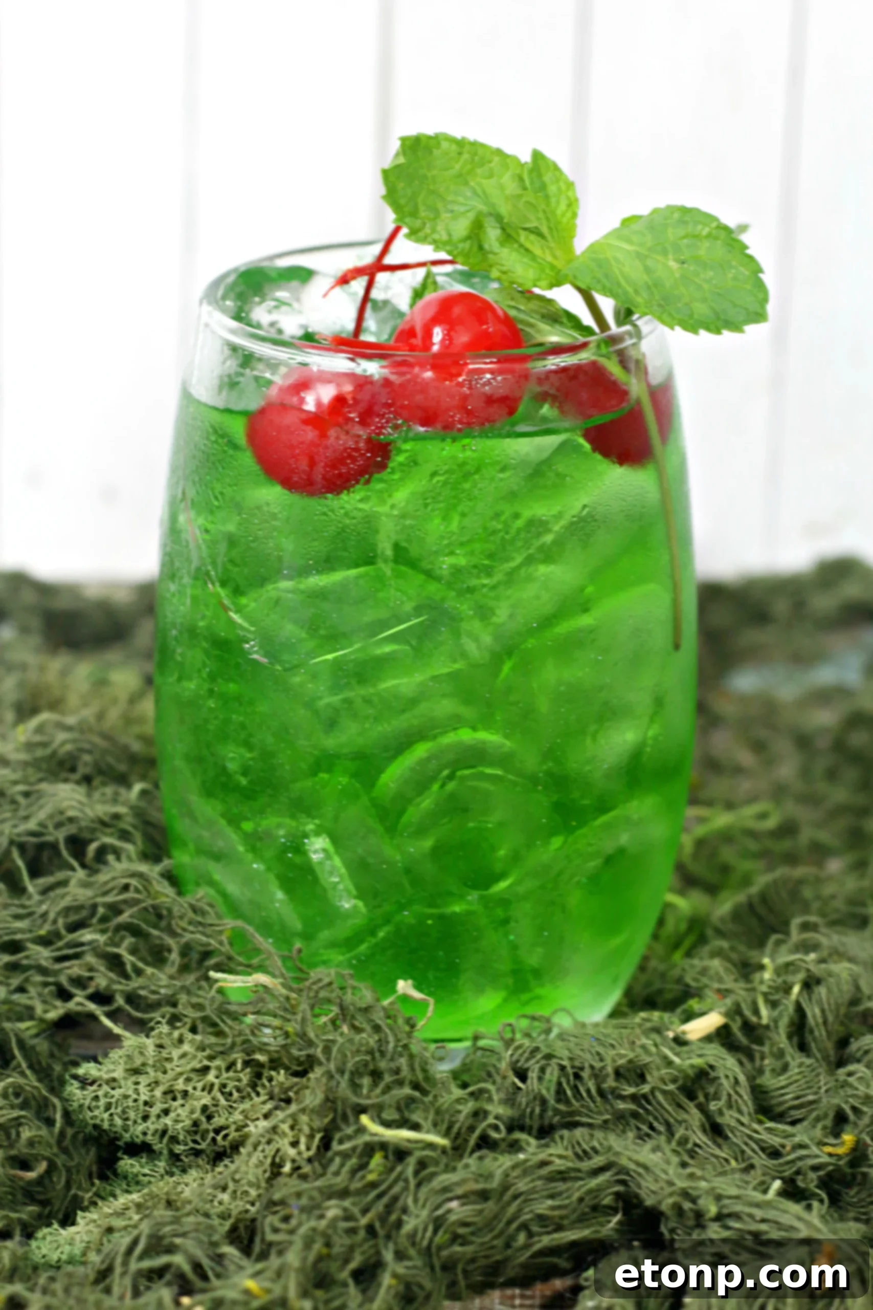 A large punch bowl filled with Liquid Marijuana Cocktail, ice, and floating fruit slices, ready for a party