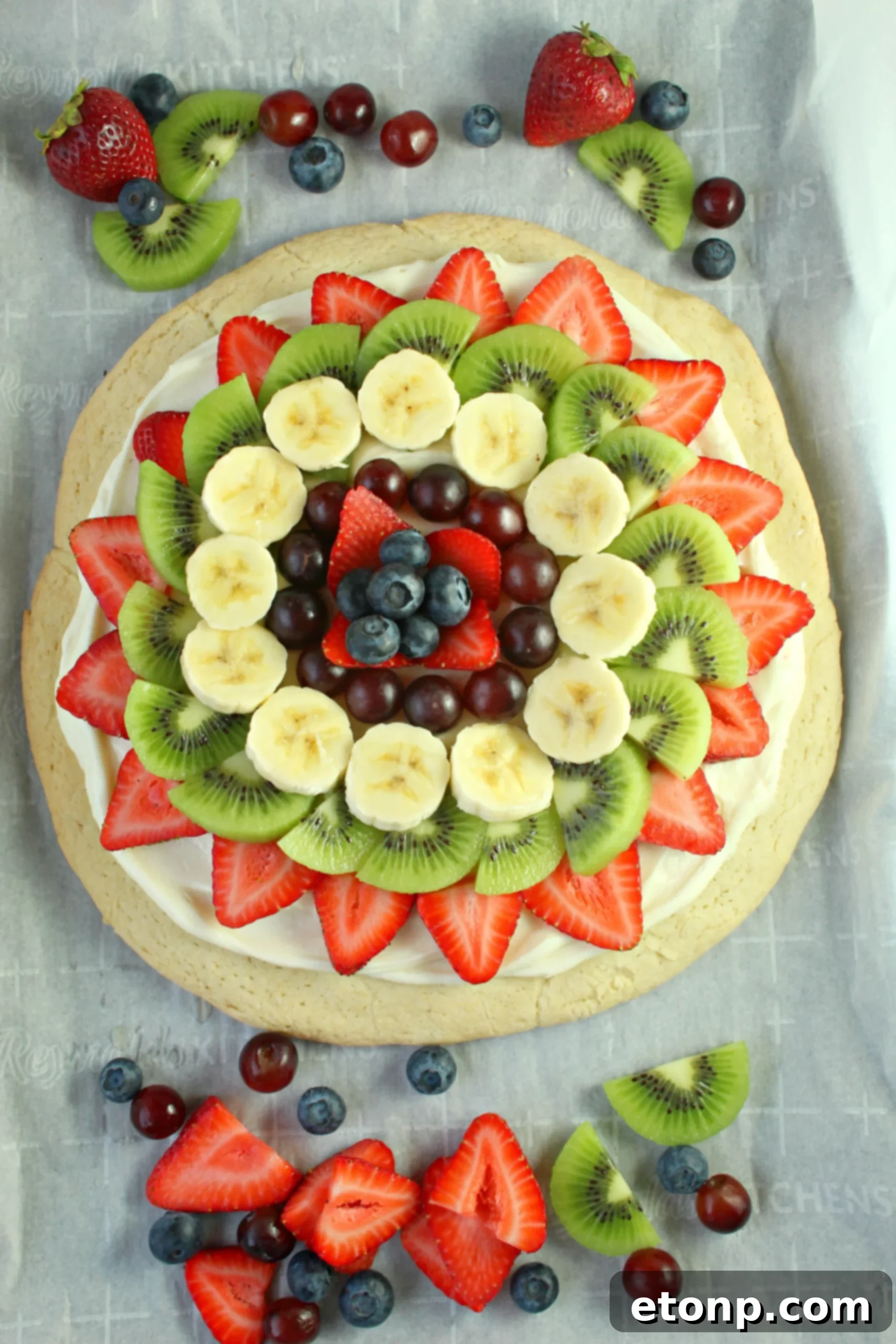 Close-up of a festive fruit pizza adorned with red berries and mint leaves, perfect for a holiday celebration.