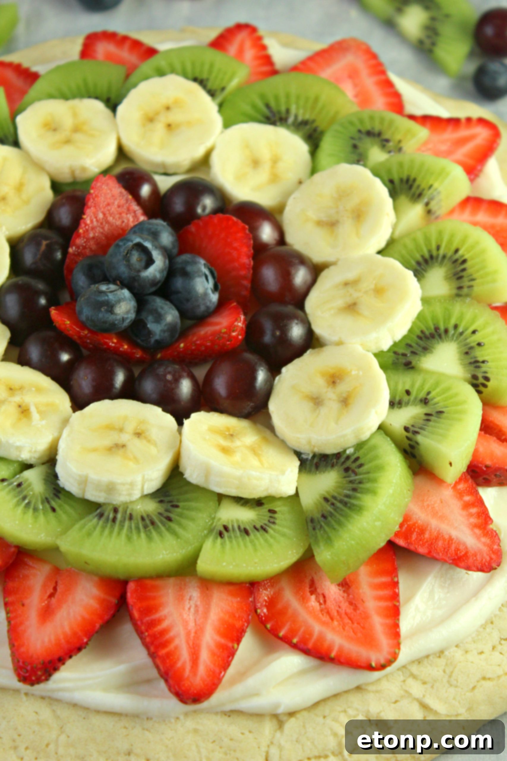 A close-up view of the fruit arrangement on a fruit pizza, showing various types of fruit beautifully placed.