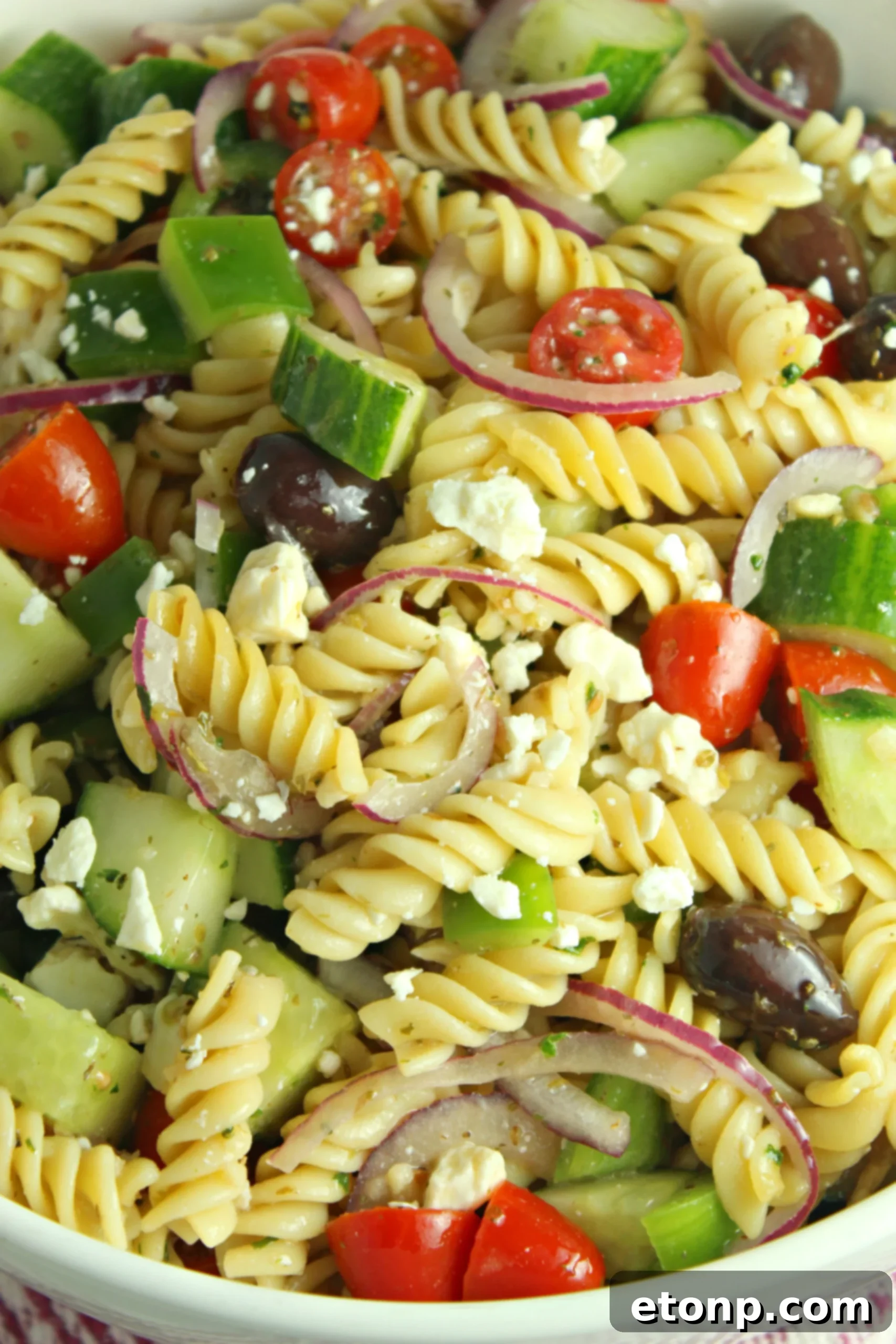 Another view of the Greek Pasta Salad with a serving spoon, ready for guests.