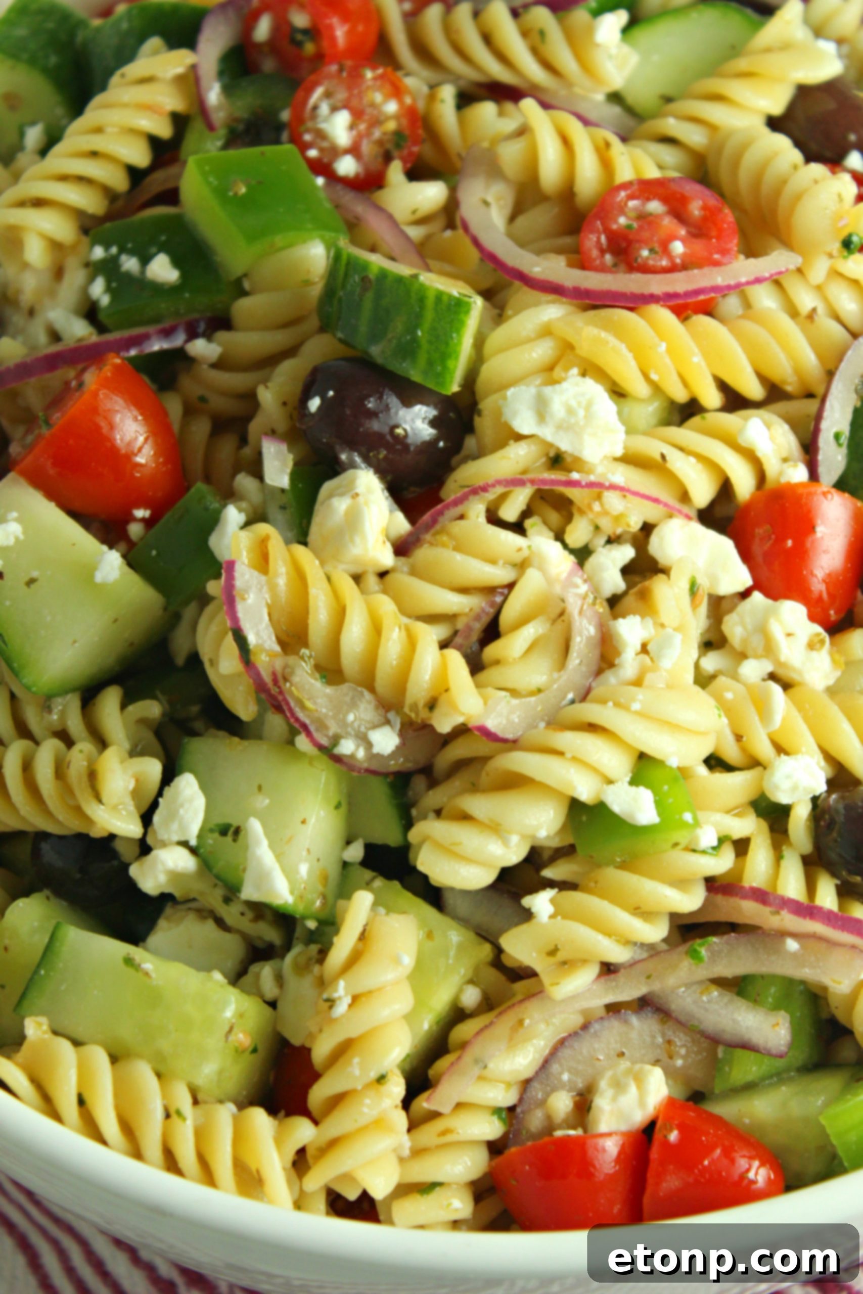 Overhead shot of a colorful Greek Pasta Salad in a large bowl, ready to be served.