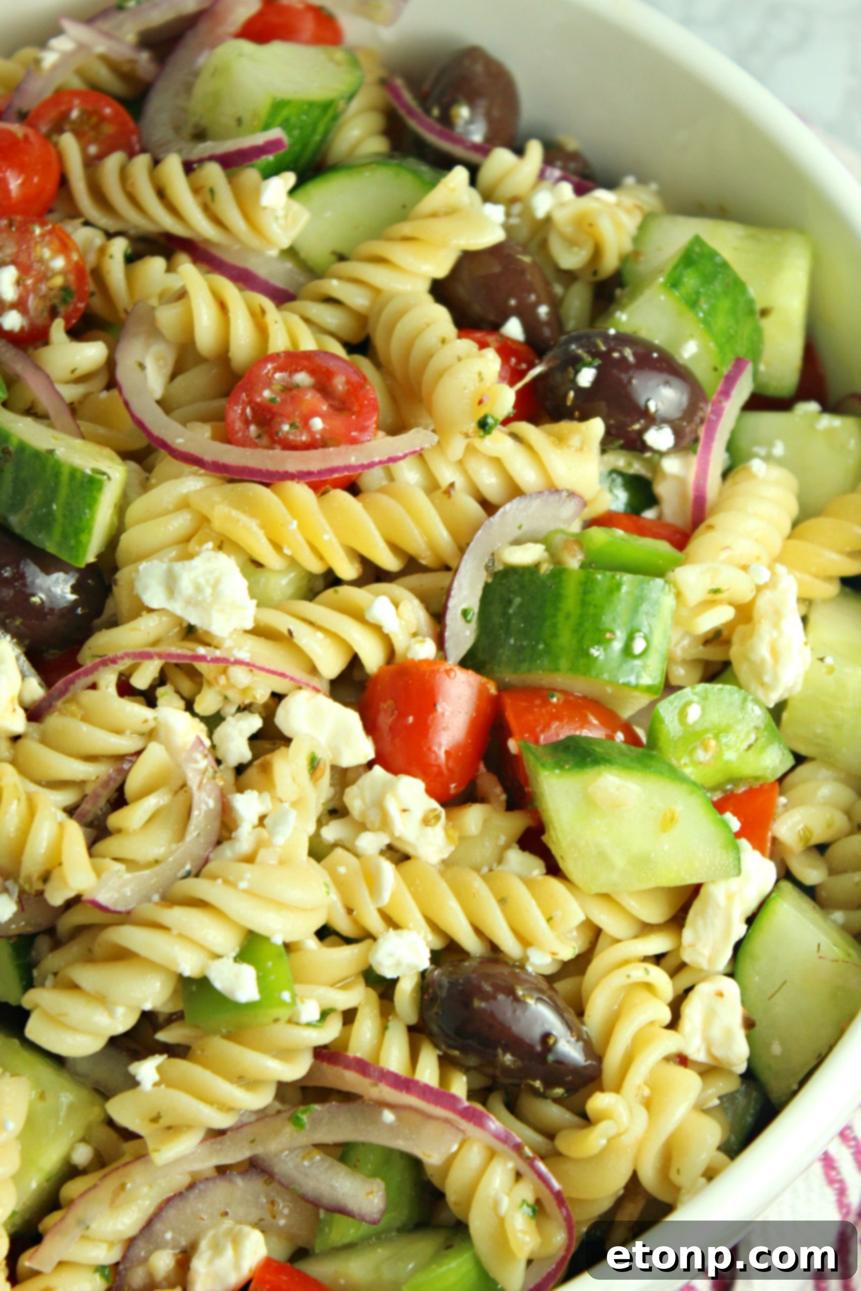 Another perspective of the Greek Pasta Salad, highlighting the mix of pasta, vegetables, and feta.
