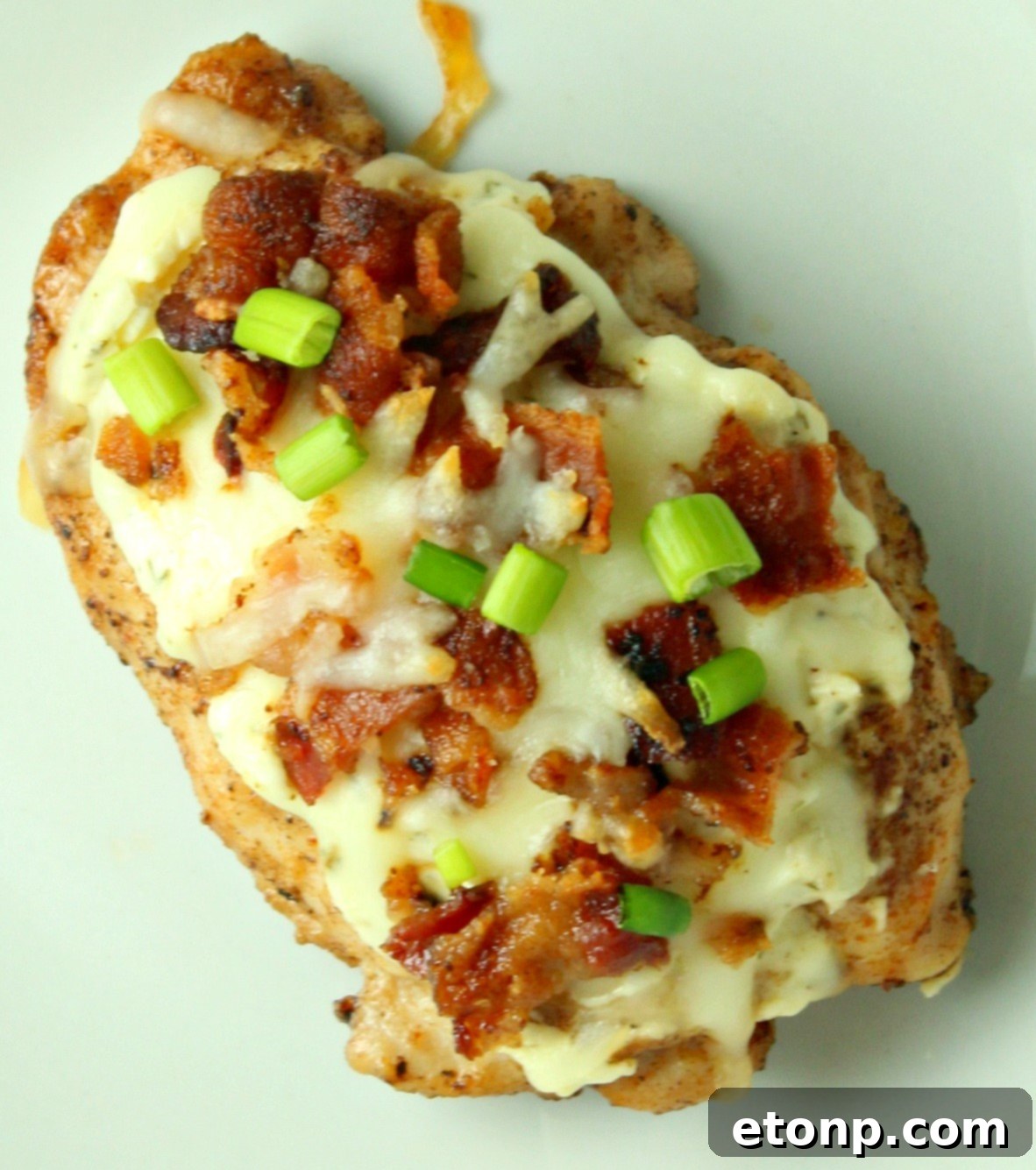 Four pieces of Smothered Crack Chicken ready to be served, garnished with fresh green scallions
