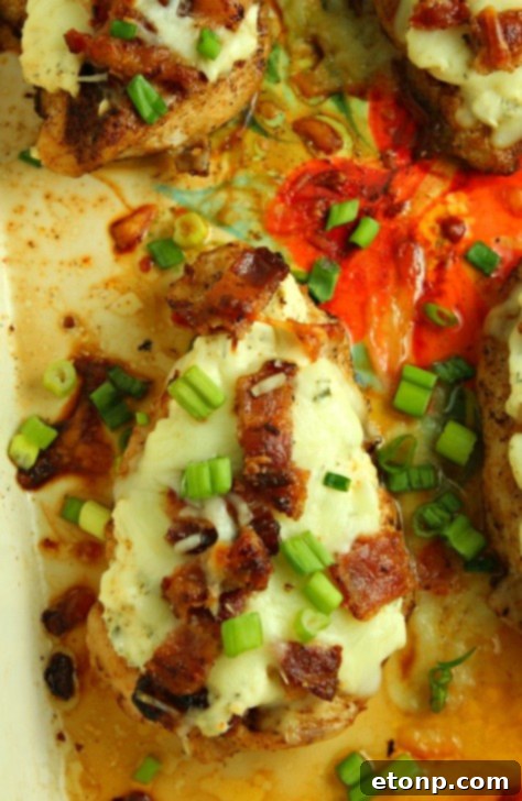 Smothered Crack Chicken cooling on a wire rack after baking, with bubbling melted cheese and bacon