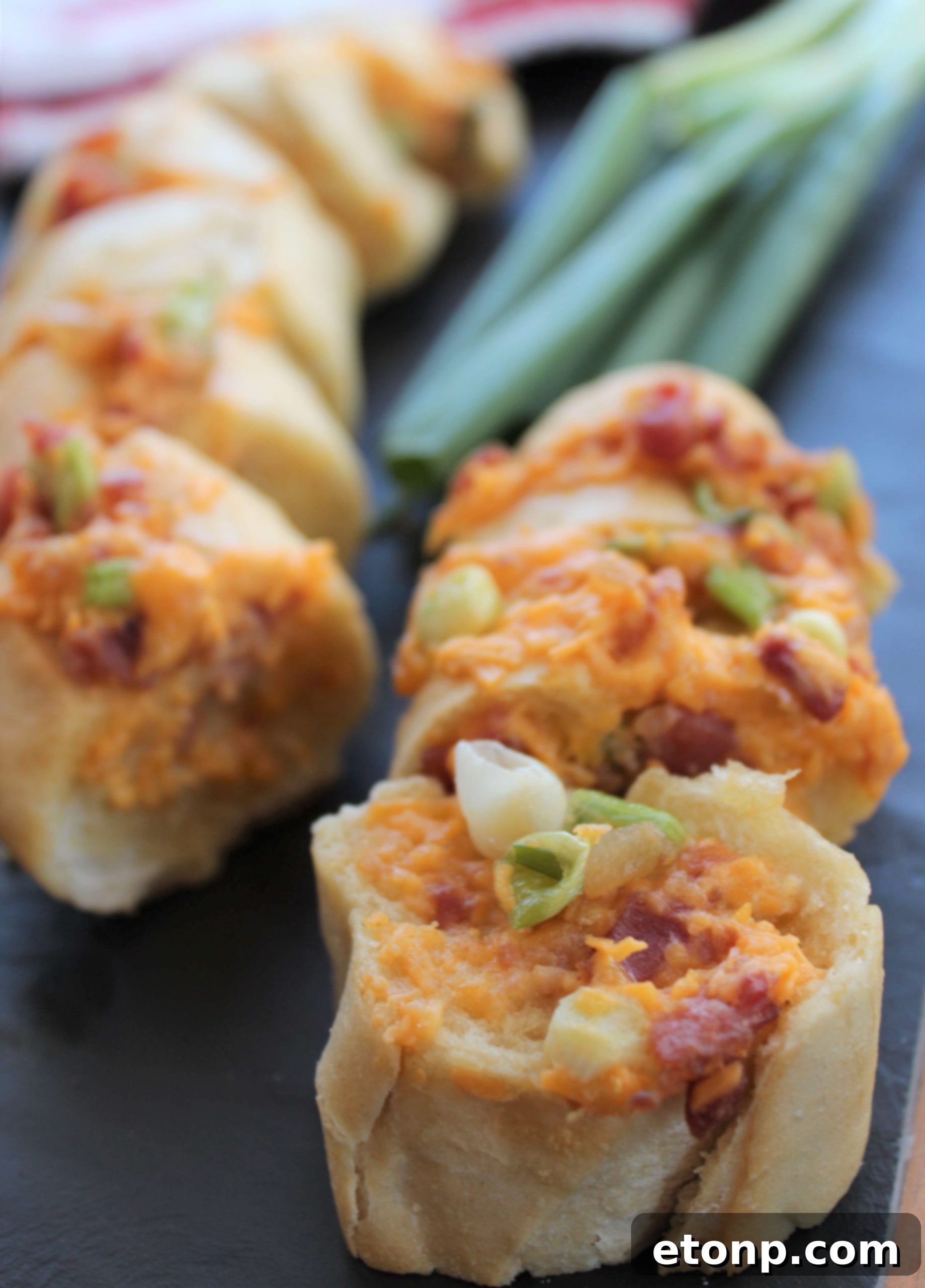 Close-up of the prepared baguette, partially sliced and filled with the cheddar bacon garlic mixture, ready for baking.