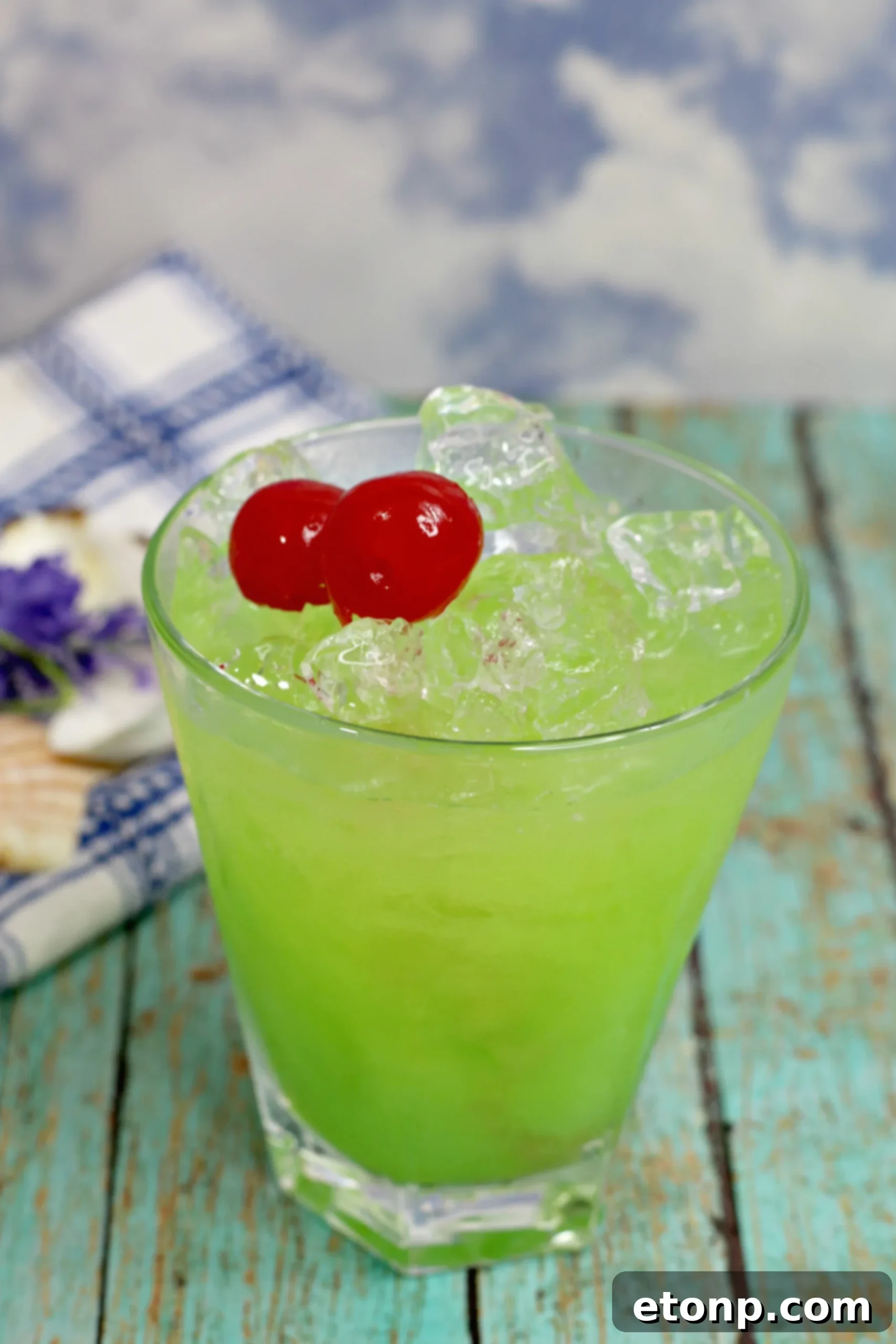 A close-up shot of a Green Iguana Cocktail, highlighting its vibrant green color and condensation on the glass, suggesting a chilled drink.