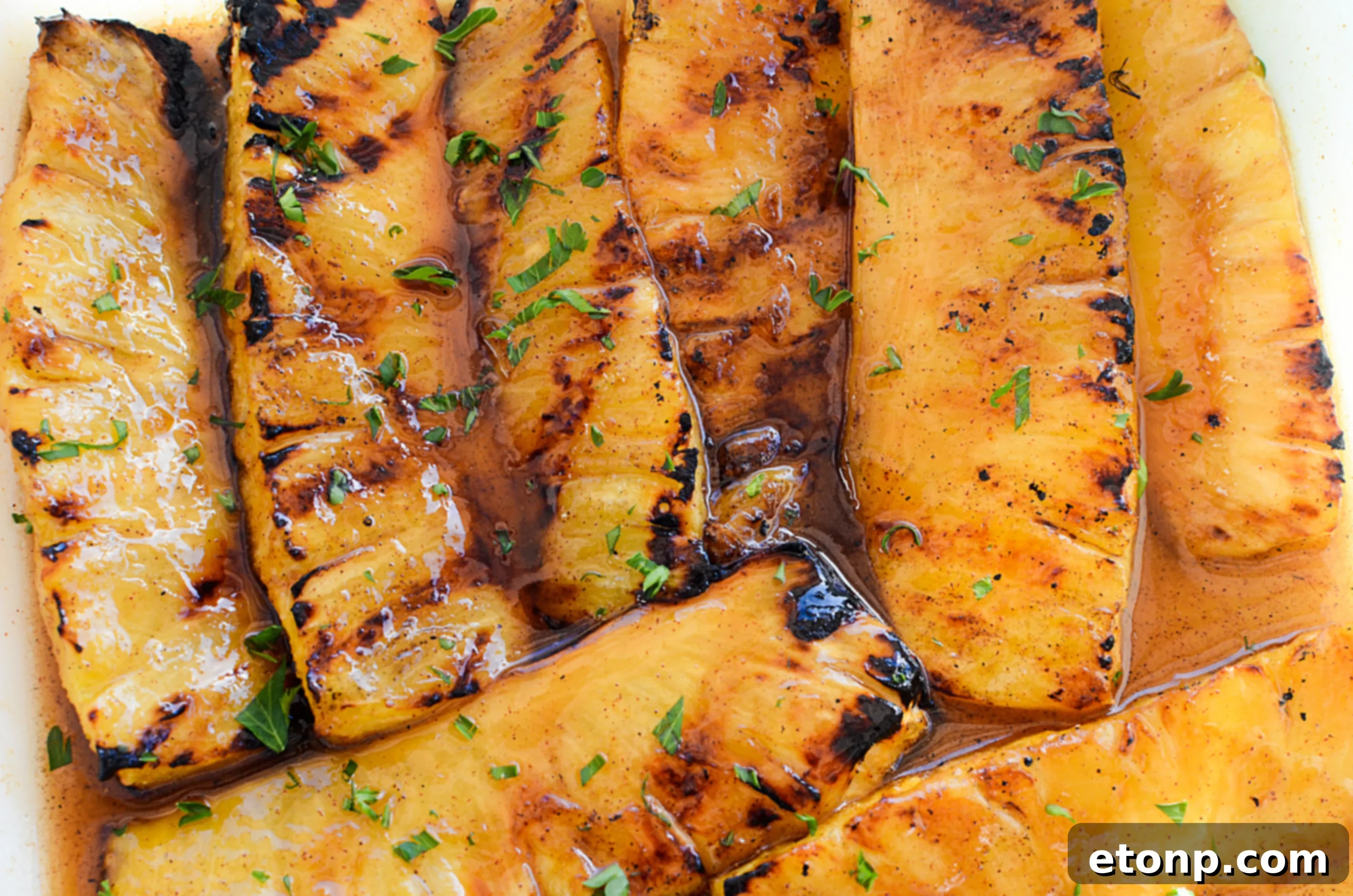 Grilled pineapple spears cooking on a hot grill, showing grill marks