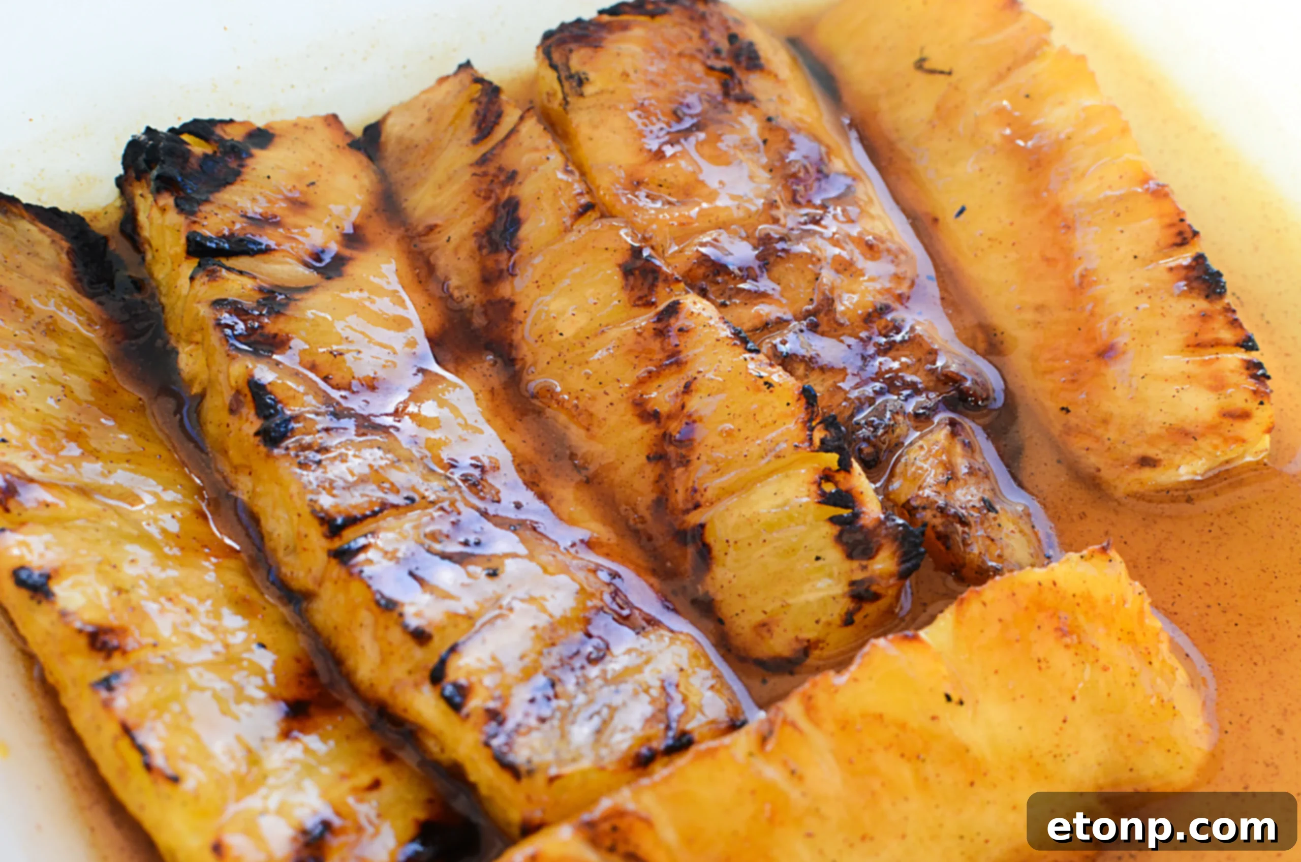 Plate of finished grilled pineapple spears, garnished with fresh mint