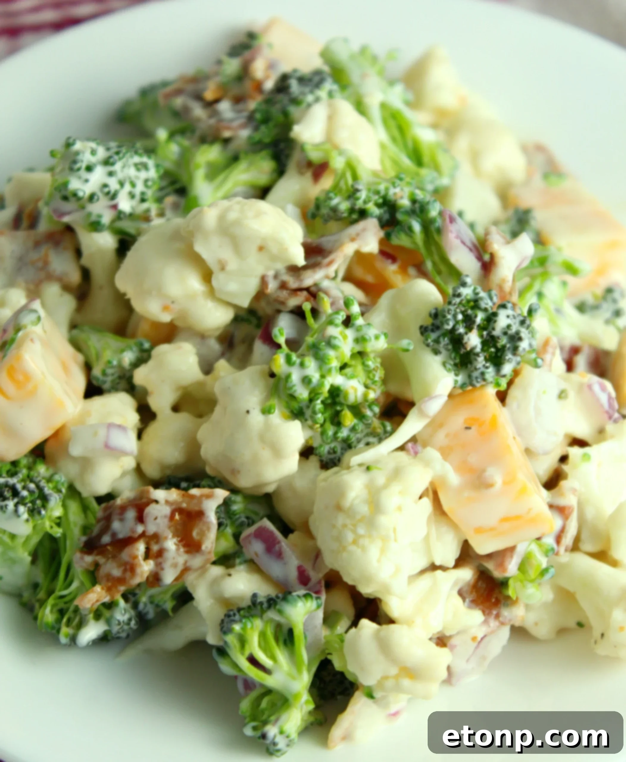Rich and Flavorful Low Carb Broccoli Cauliflower Salad 6 Ingredients for Loaded Broccoli Cauliflower Salad laid out on a cutting board, including fresh broccoli and cauliflower florets, diced bacon, and cheese.