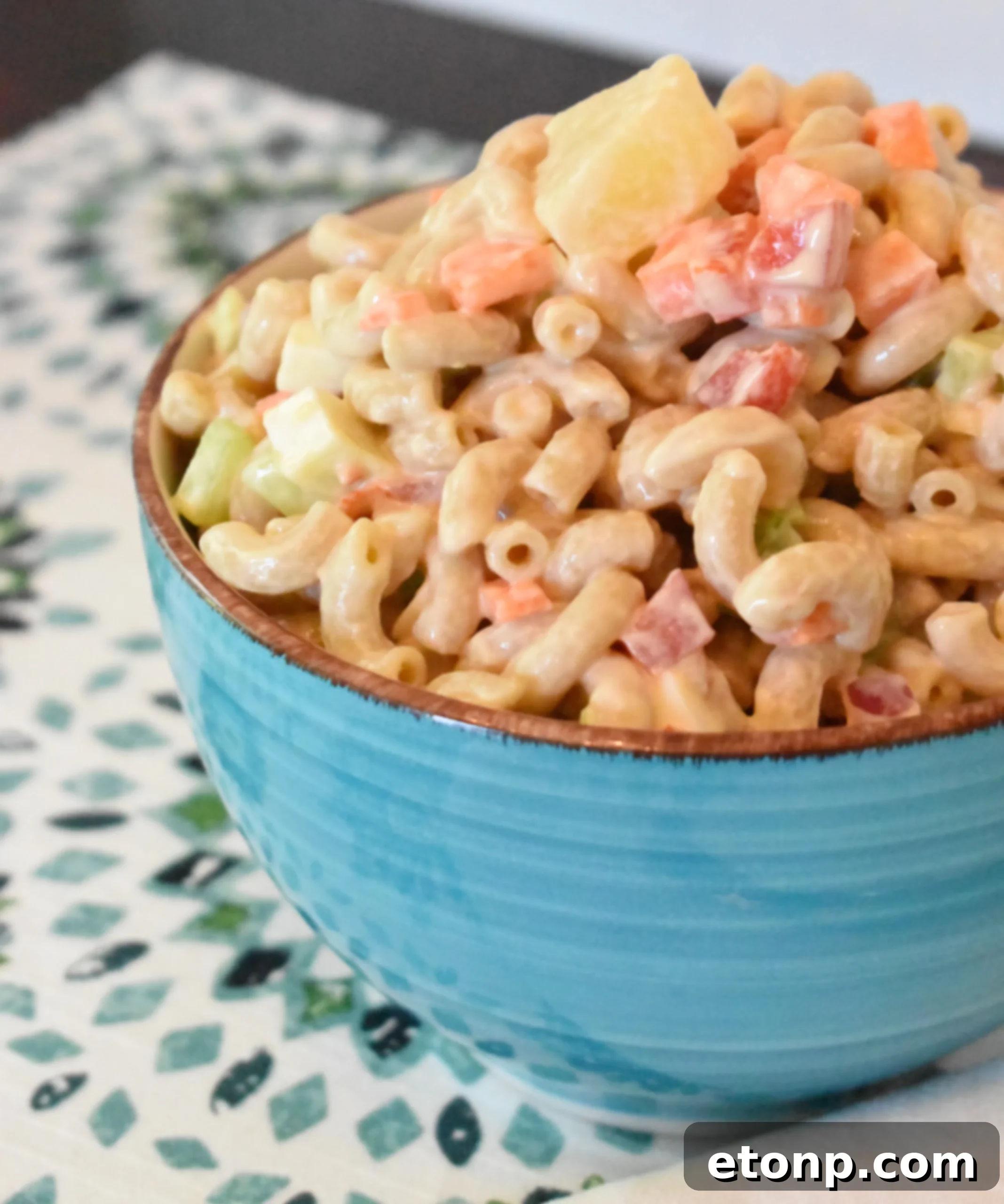 Paradise Macaroni Medley 2 A vibrant bowl of Tropical Macaroni Salad, featuring macaroni, colorful vegetables, and pineapple chunks, perfect for summer gatherings.