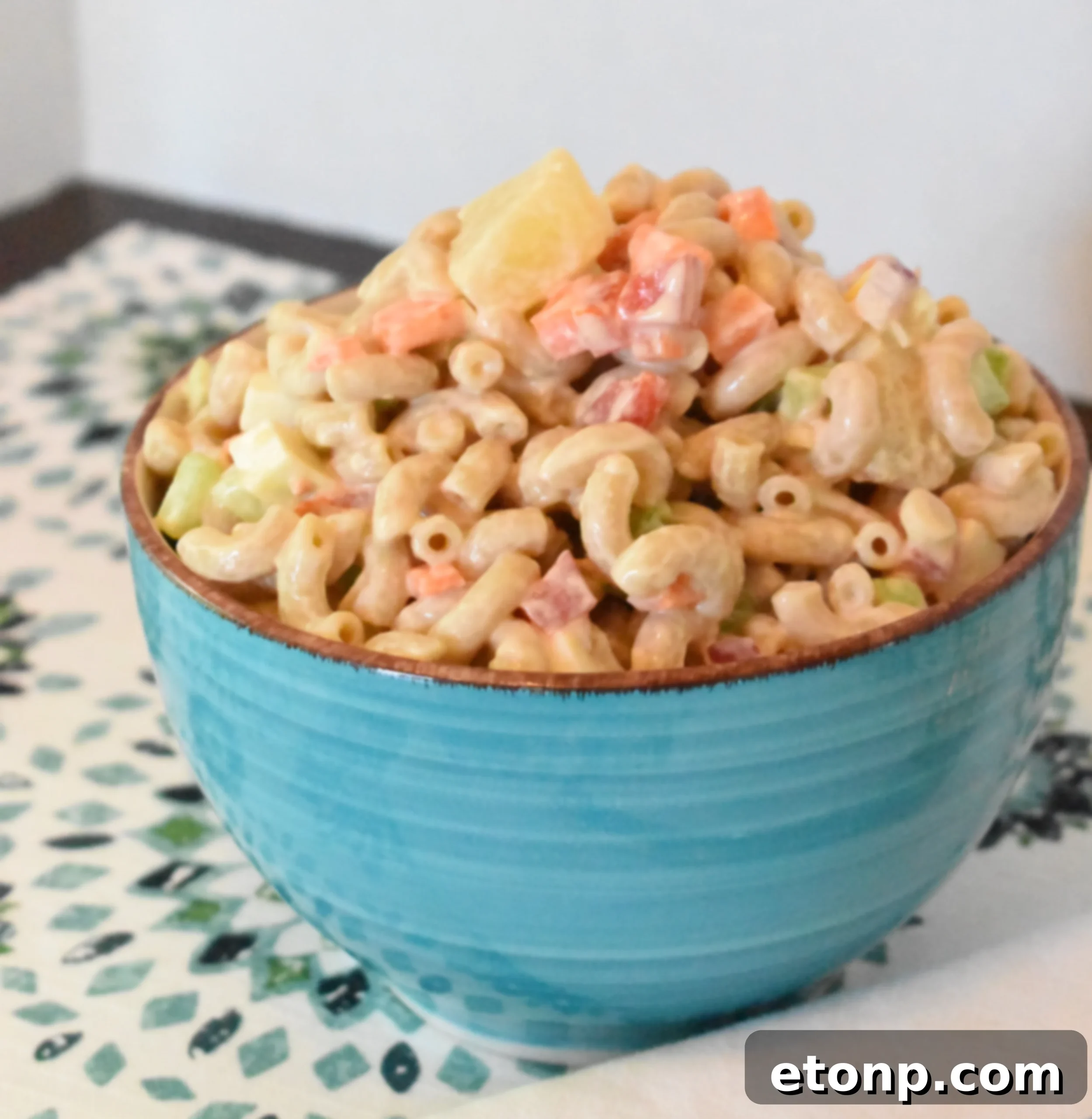 Paradise Macaroni Medley 6 A serving of Tropical Macaroni Salad on a plate, garnished with a sprig of parsley, emphasizing its fresh and appealing look.