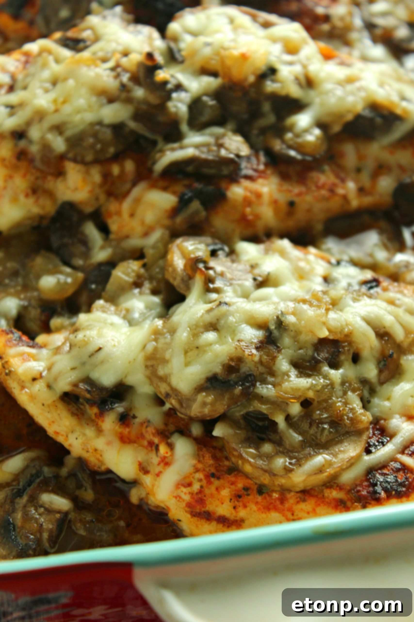 A serving of Smothered Cheesy Baked Chicken with Mushrooms, highlighting the tender chicken and the rich topping.